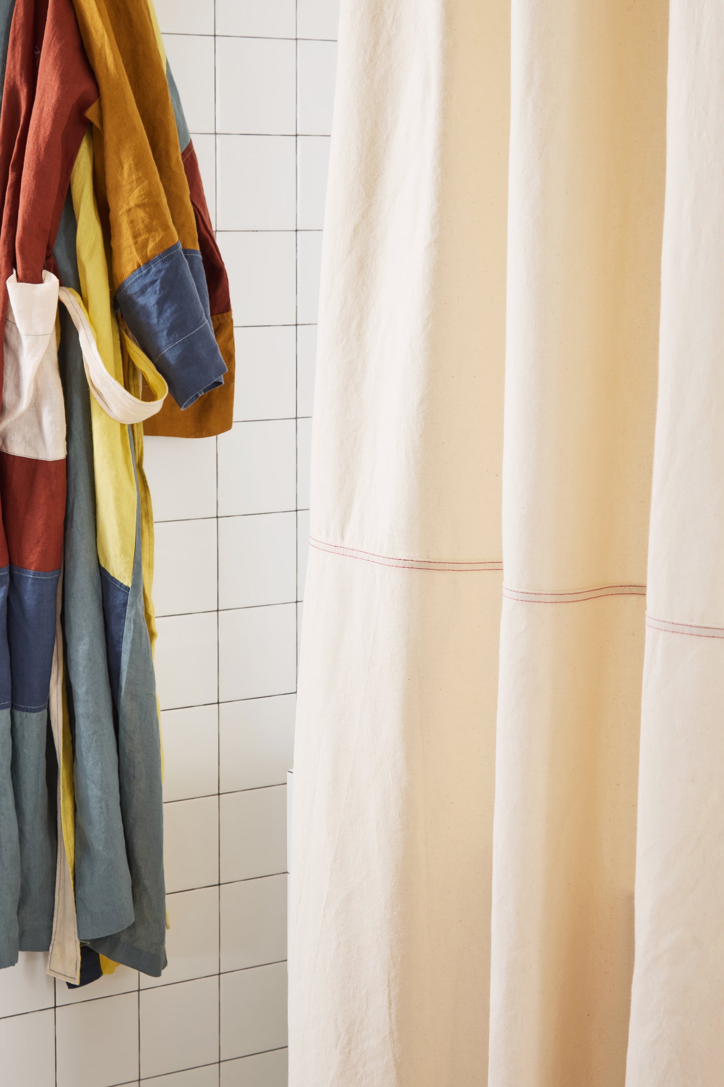 cream curtain with red stitching and color-blocked robe.