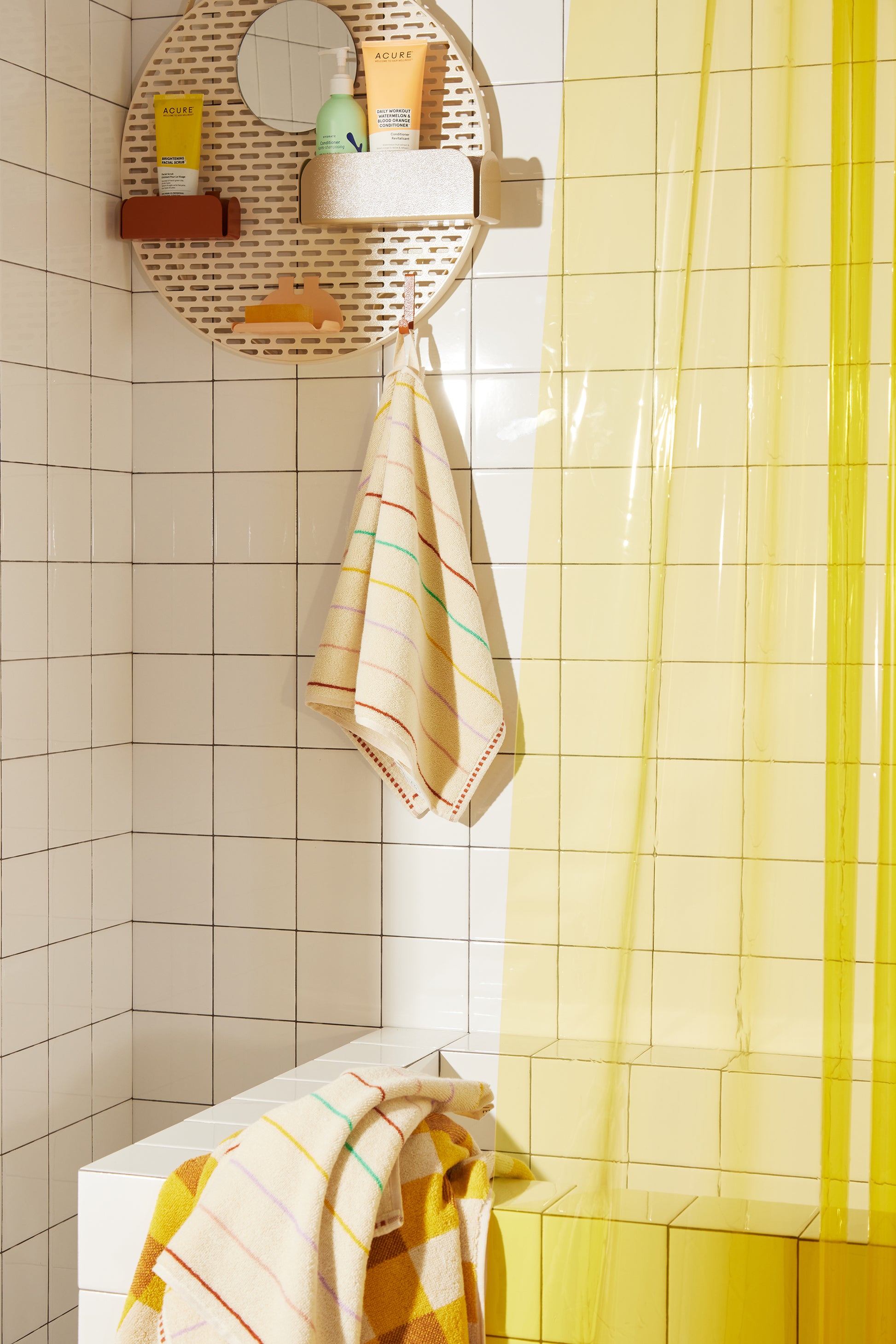 Prism hand towel styled in white tiled bathroom next to the spot shower organizer, and the sunny sun shower curtain.