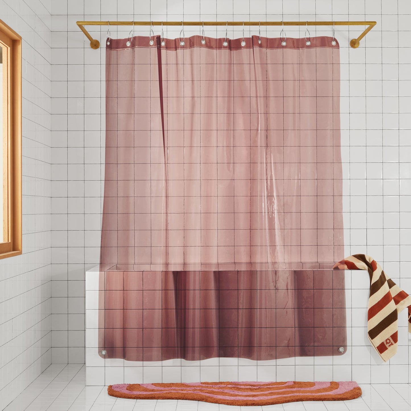 Sun shower curtain in rose hanging over bathtub styled in a white tiled bathroom with lost coast holiday.