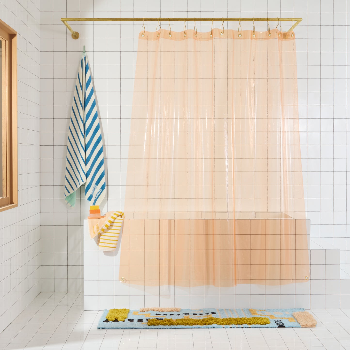 Sun shower curtain in peony hanging over bathtub styled in a white tiled bathroom.
