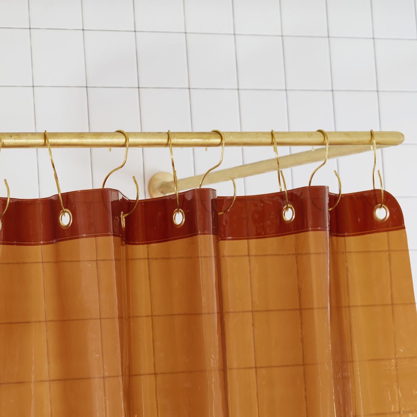 Sun Shower Honey detail view of grommets and hooks hanging from shower curtain rod.