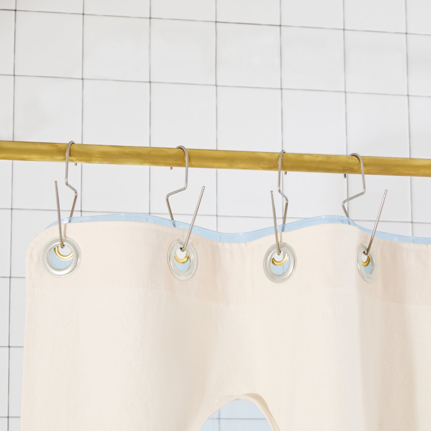 Bubble Pine detail view of grommets and hooks hanging from shower curtain rod.