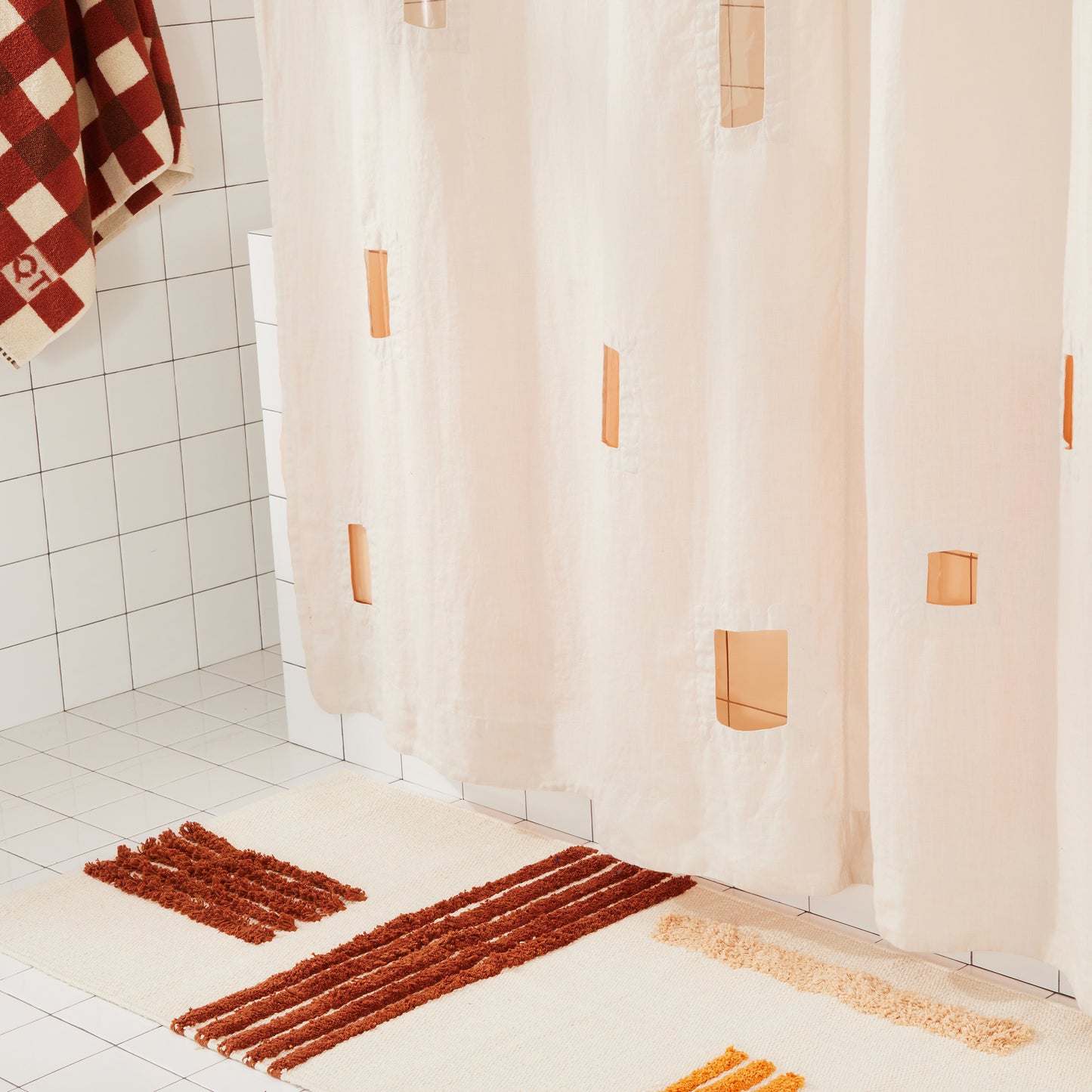 Ronchamp linen shower curtain details rectangular cutouts and hangs above reyes bath mat in clay.