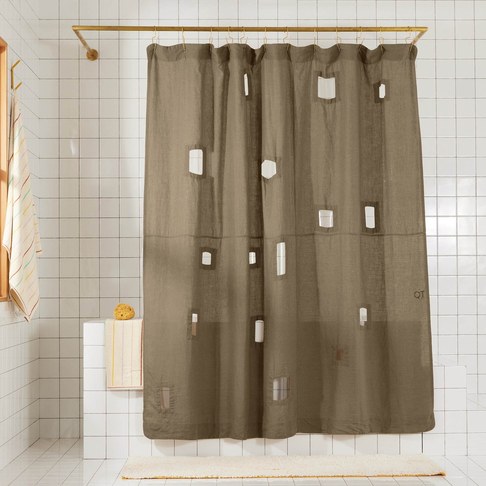 Ronchamp linen curtain in olive hanging in shower in white tiled bathroom.