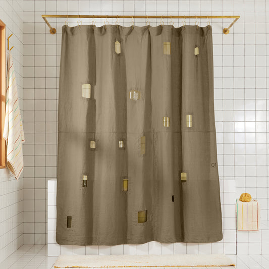 Olive green linen shower curtain with different sized rectangular window cut-outs hangs in white tiled bathroom.