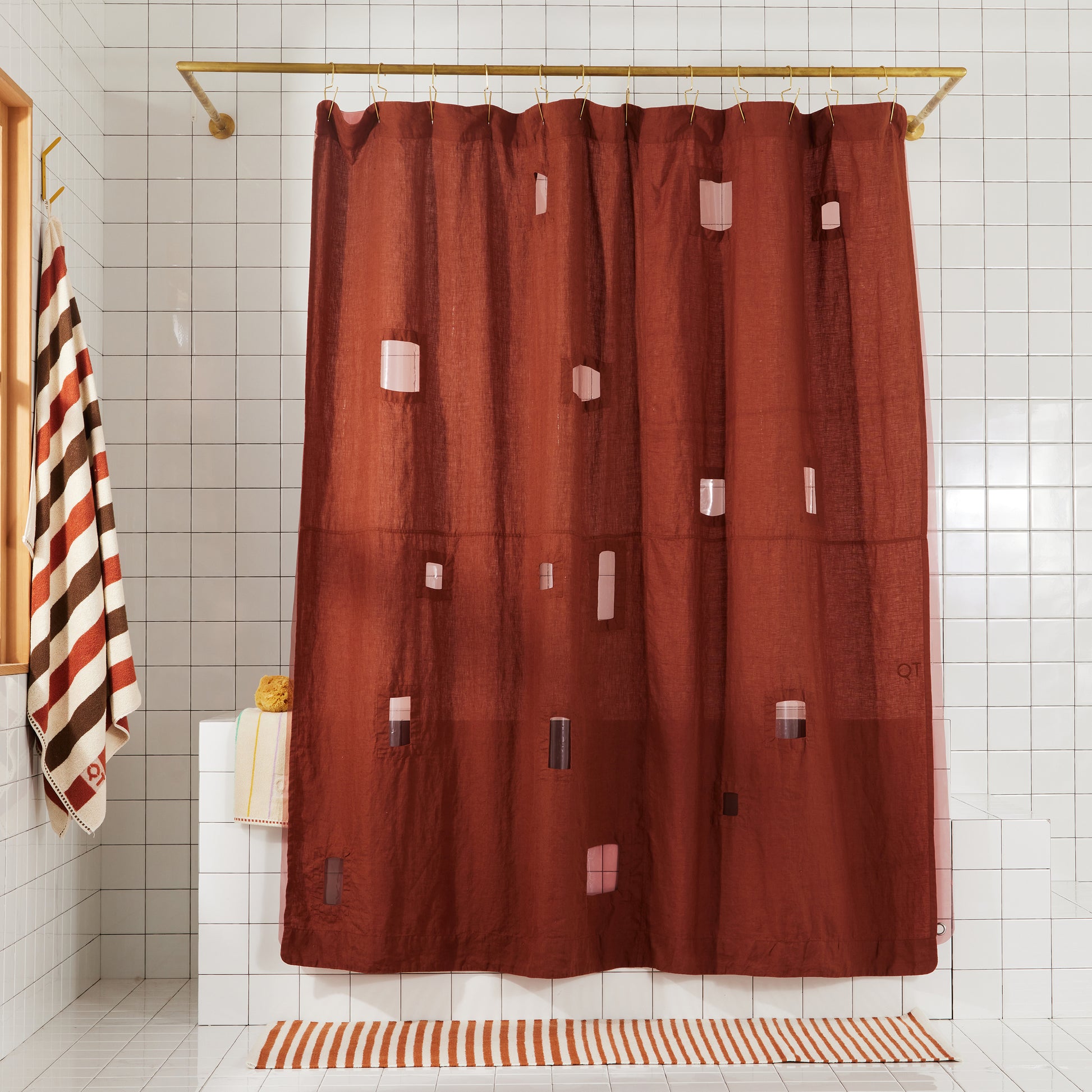 Burgundy linen shower curtain with assortment of cut out window squares hanging in white tiled bathroom.