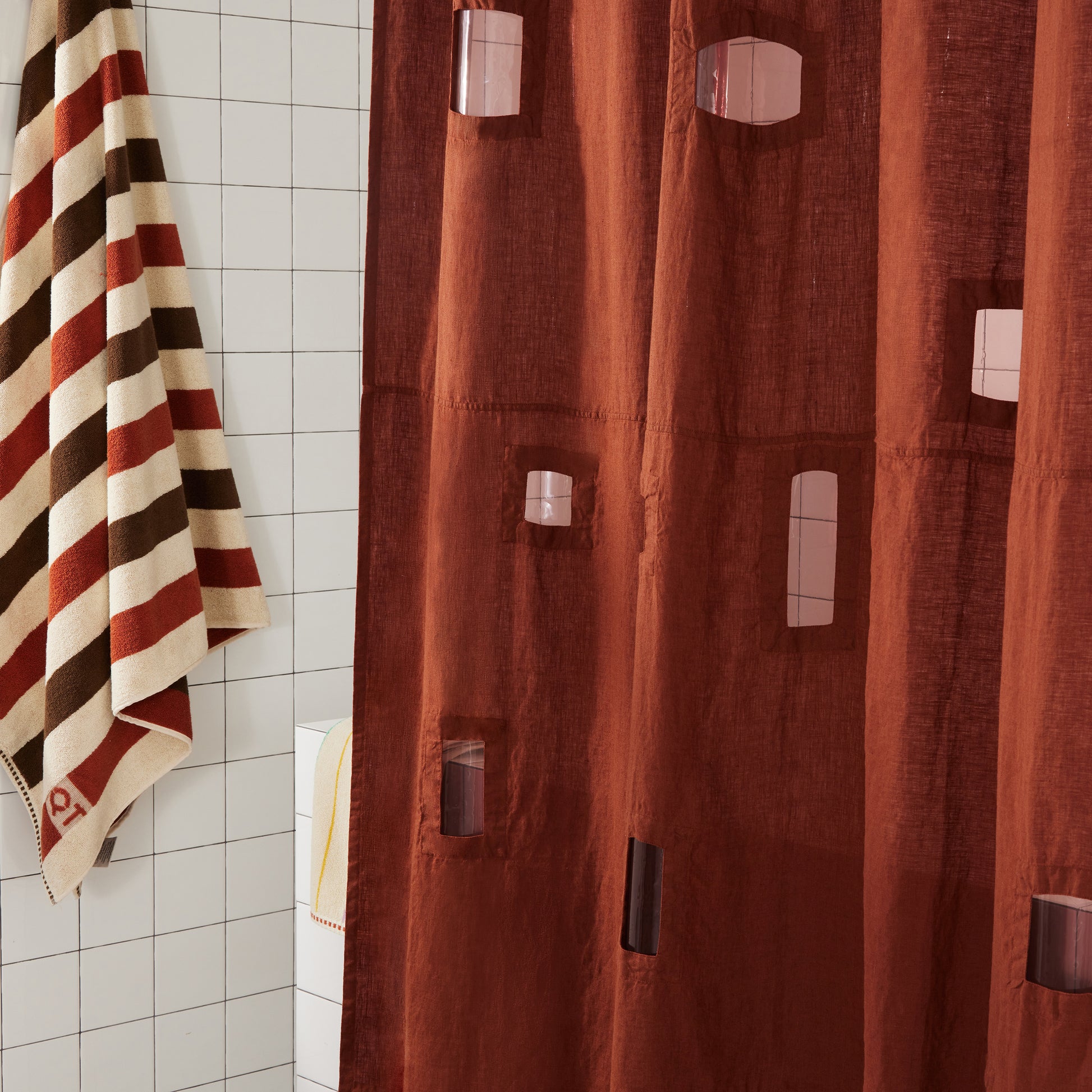 Side shot of burgundy linen shower curtain with assorted rectangular shapes of window cutouts.