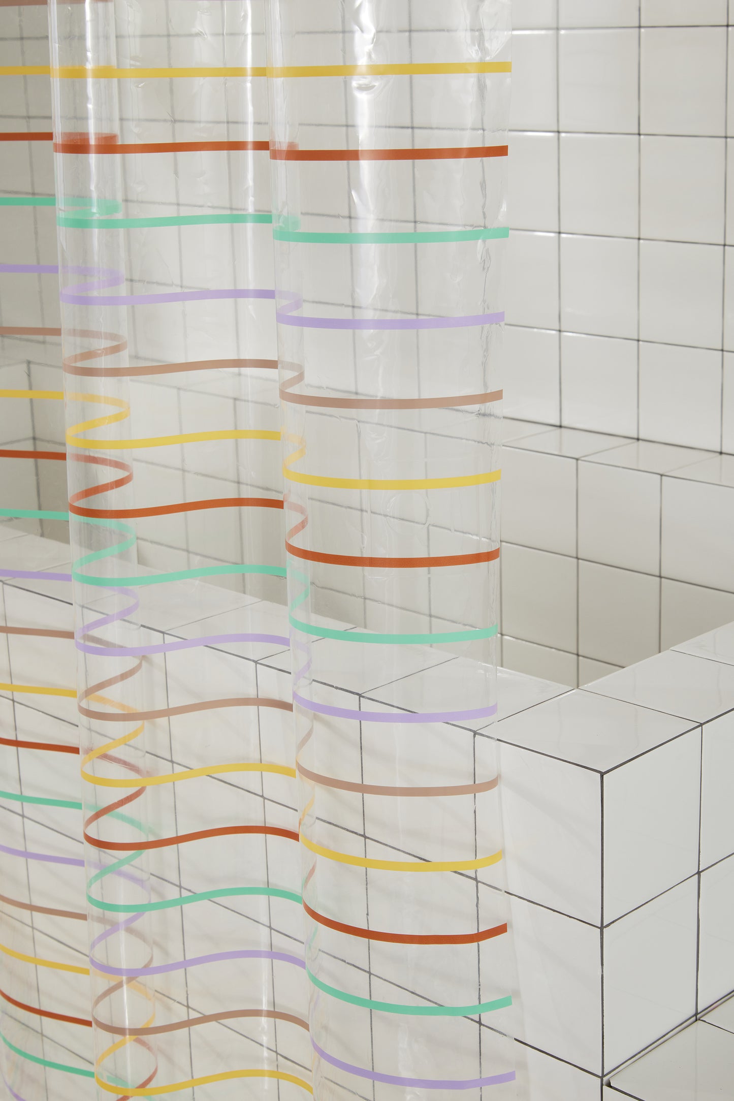 Side view of shower curtain with multicolor horizontal pinstripes. Stripes are green, lavender, rose, yellow, clay.