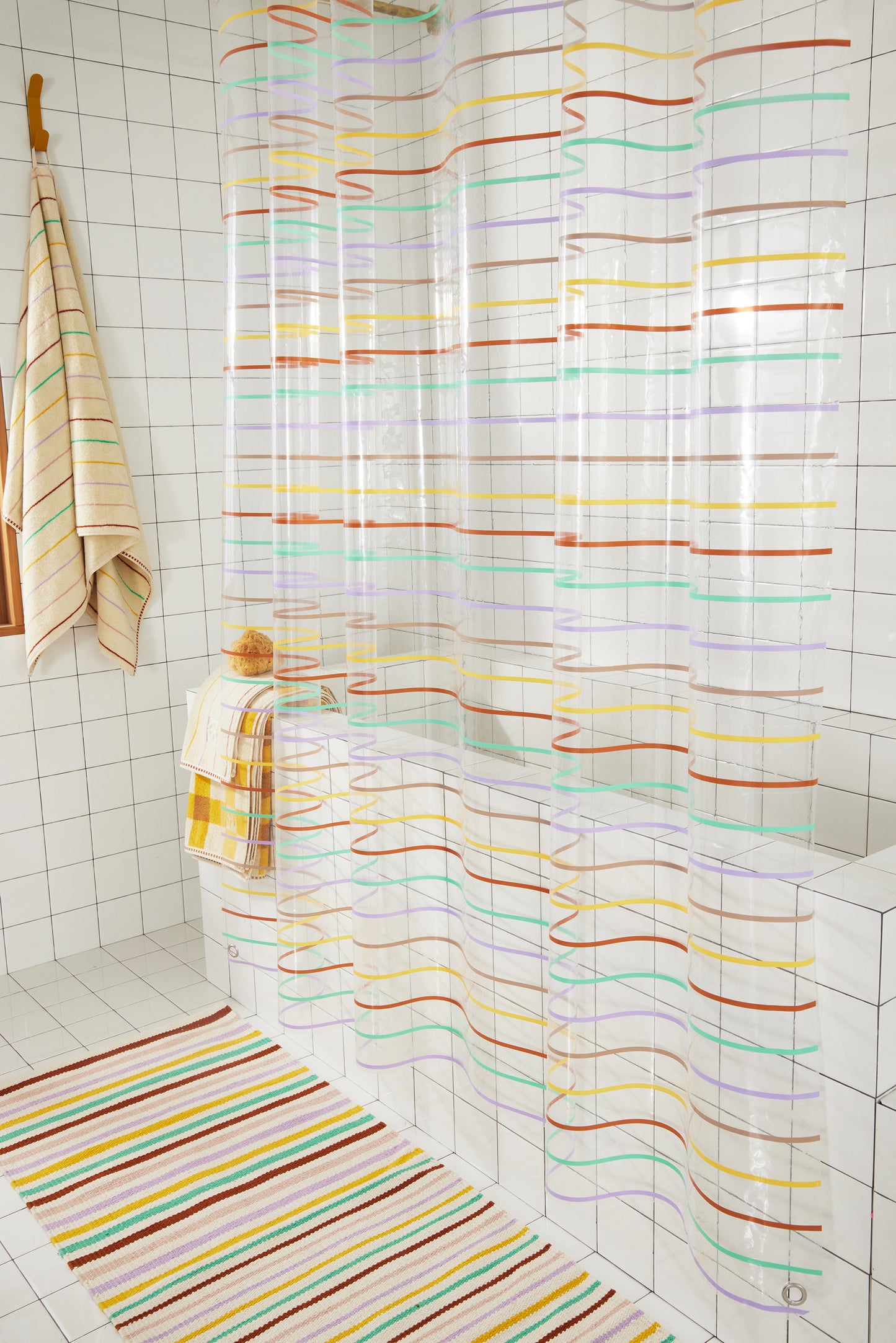 Full length side view of shower curtain with multi-color pinstripes. This view also features Prism towel and Prism rug which is not yet live and coming soon.