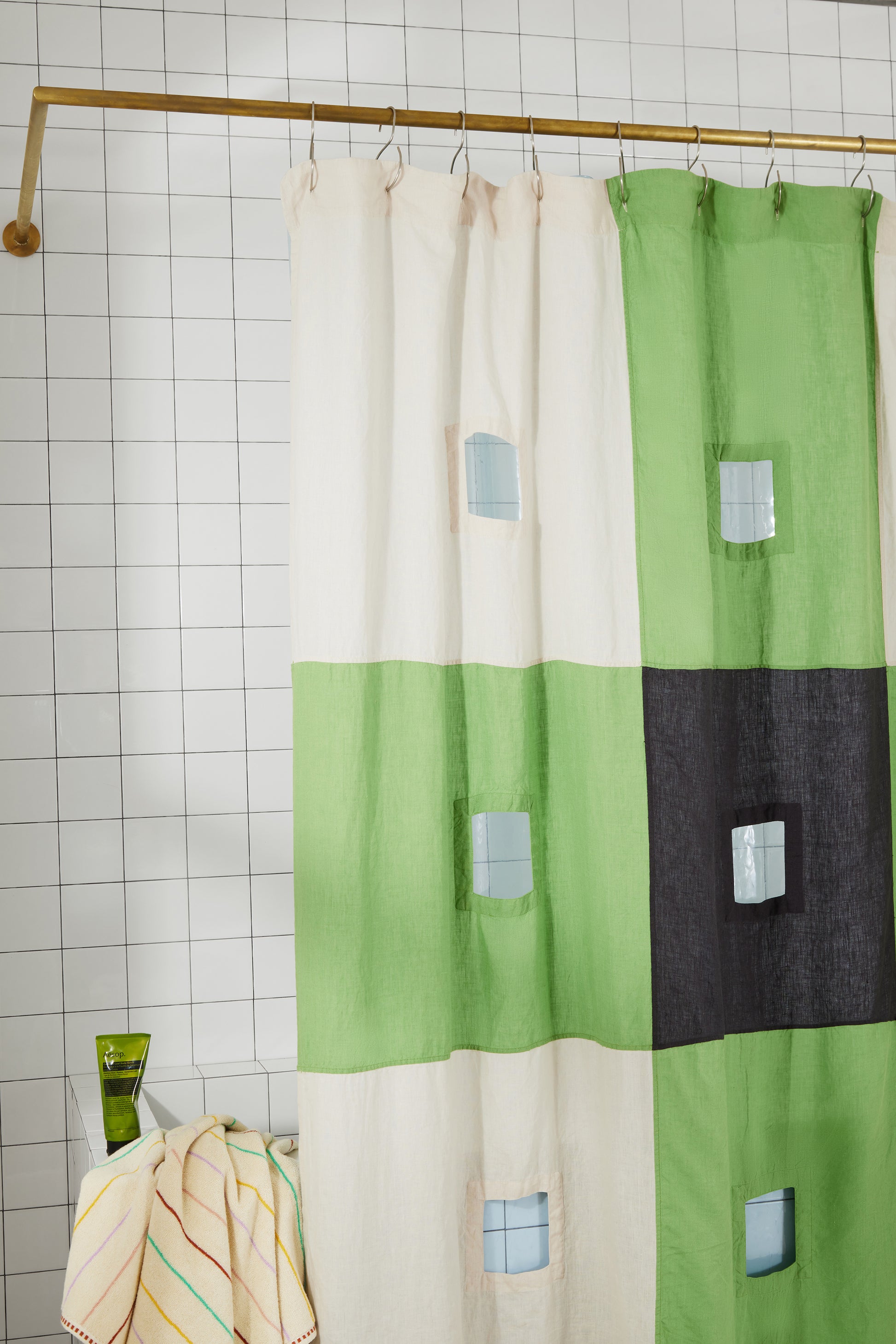 photo of top left corner of green and charcoal linen curtain hanging in bathroom.