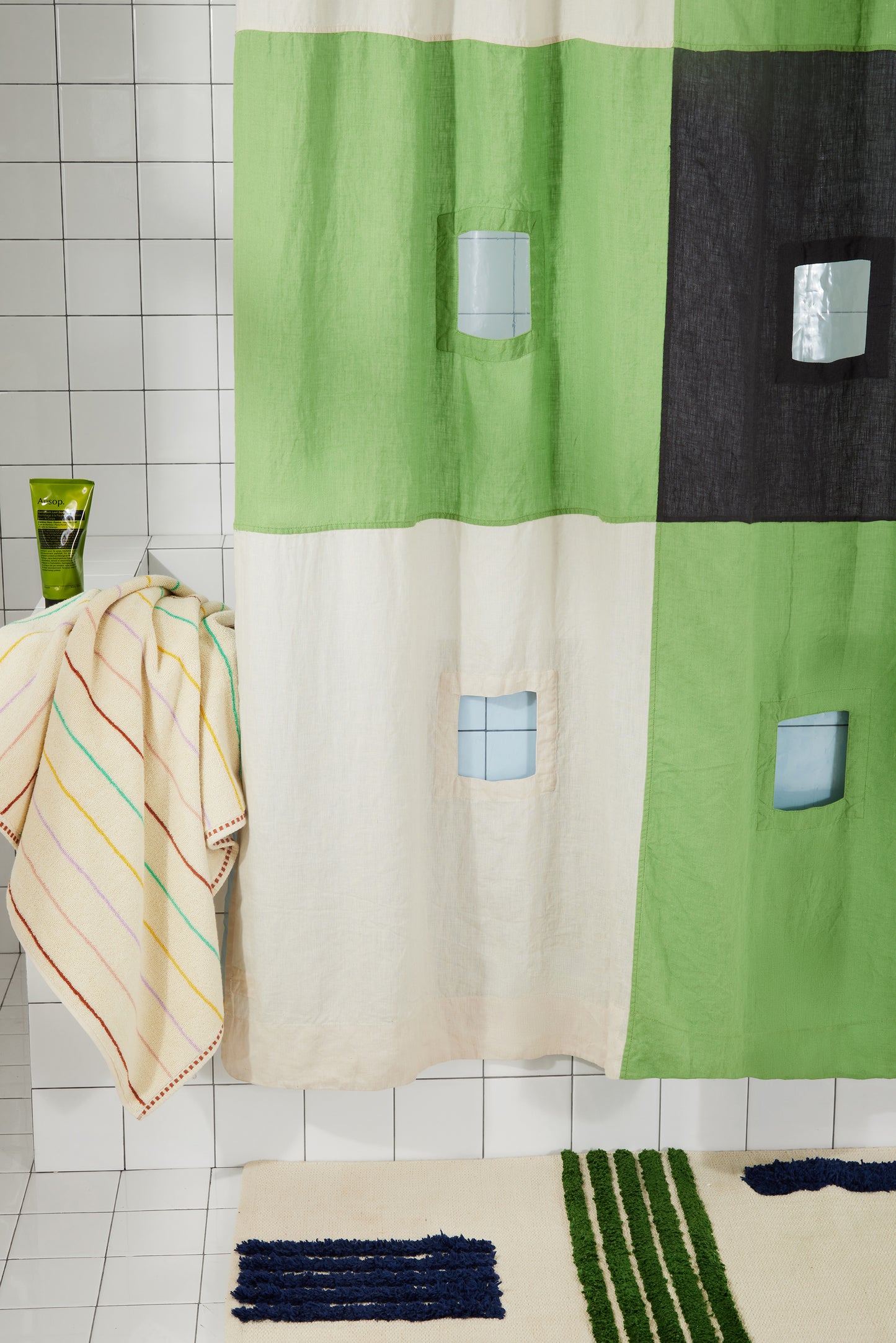 Photo of bottom left corner of green and charcoal linen curtain hanging in bathroom.