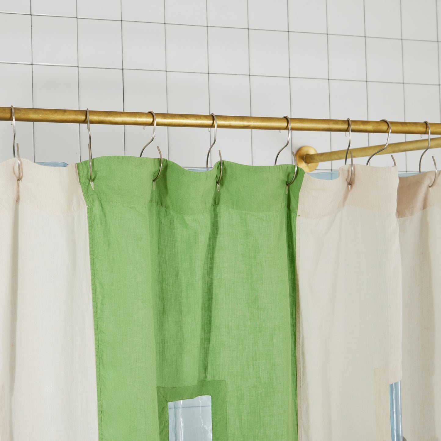 photo of top hem of green linen curtain with button holes and shower curtain hooks