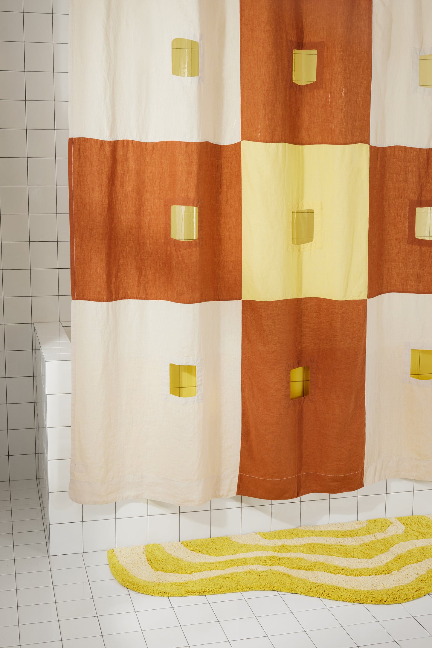 left side of clay and yellow checker linen shower curtain is featured hanging in bathroom.