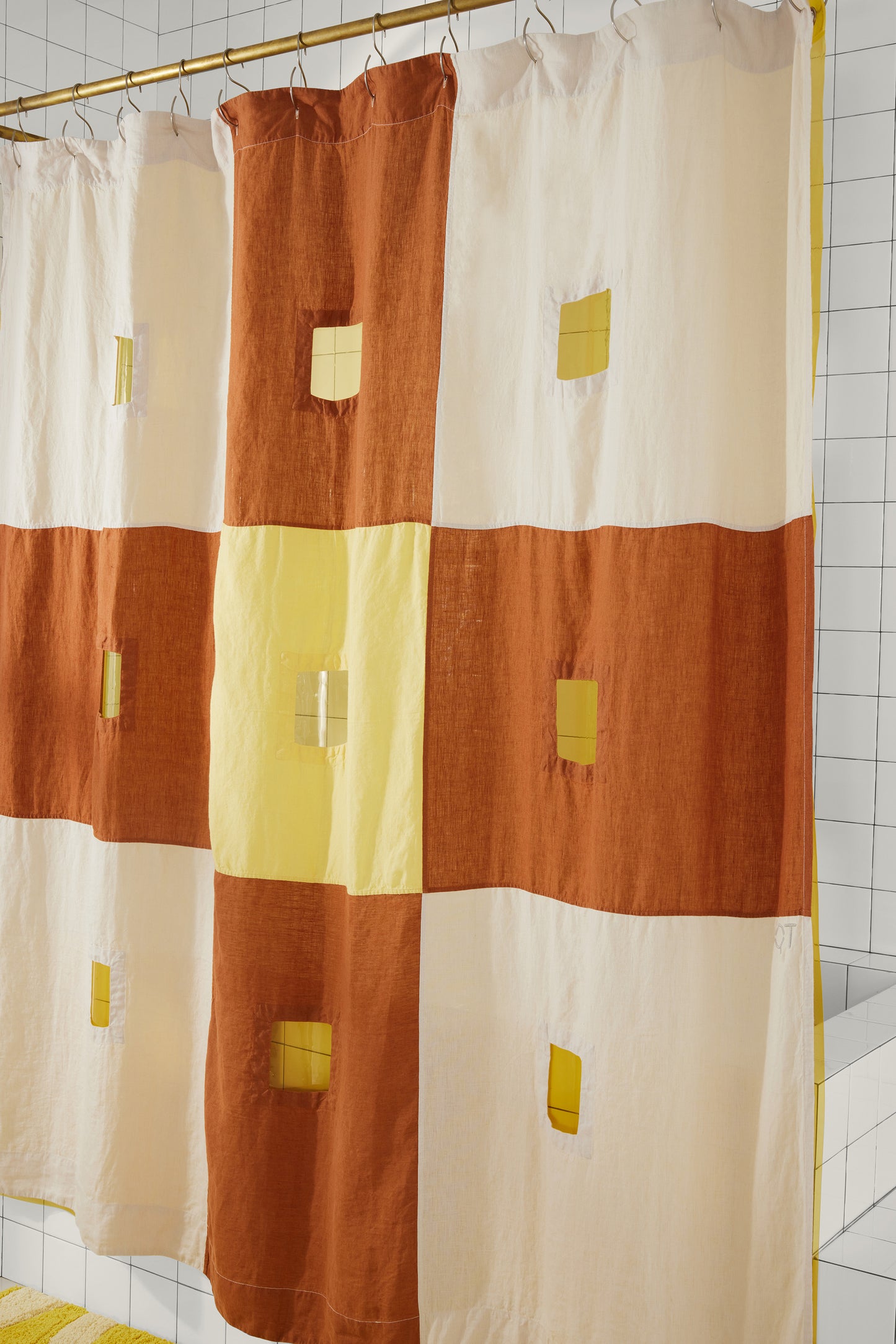 Right side of clay and yellow checker linen shower curtain is featured hanging in bathroom.