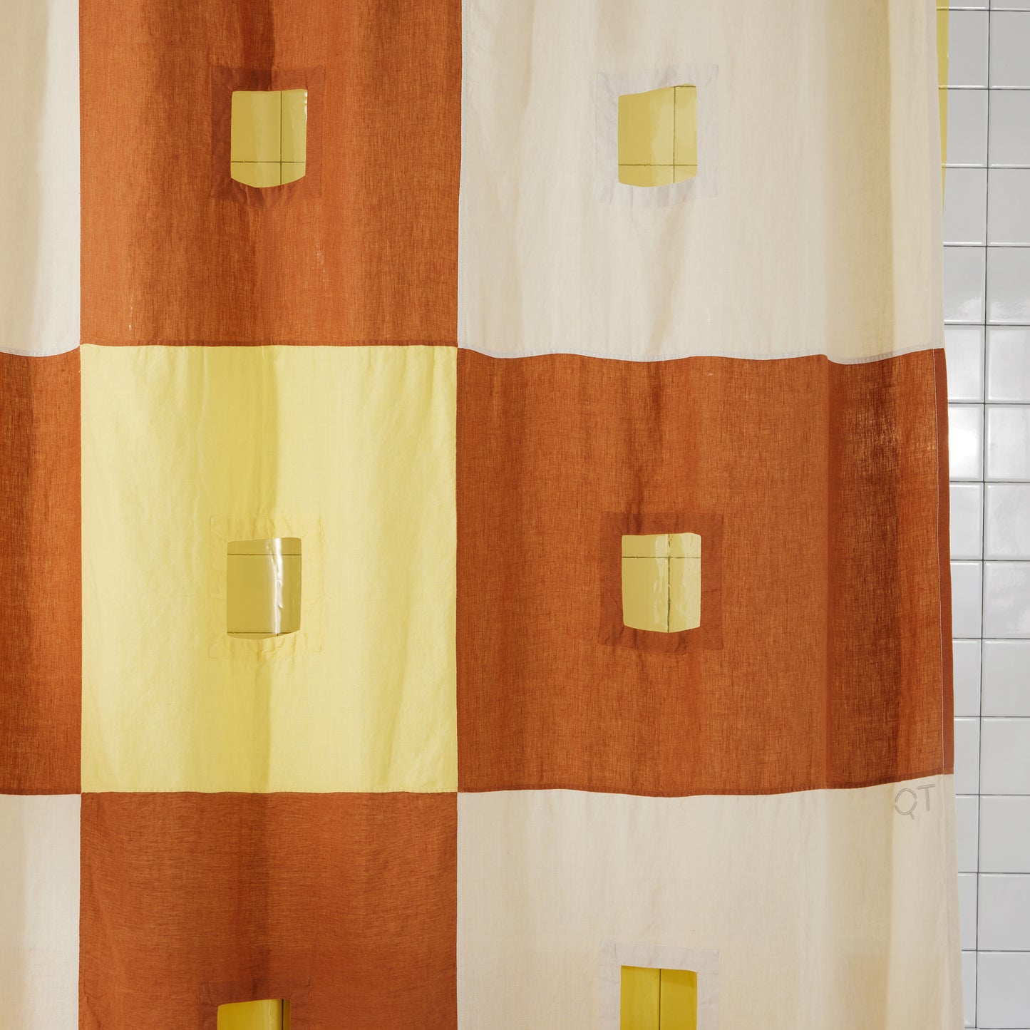 Center cut outs in the clay and yellow checker linen shower curtain are featured in this photo.