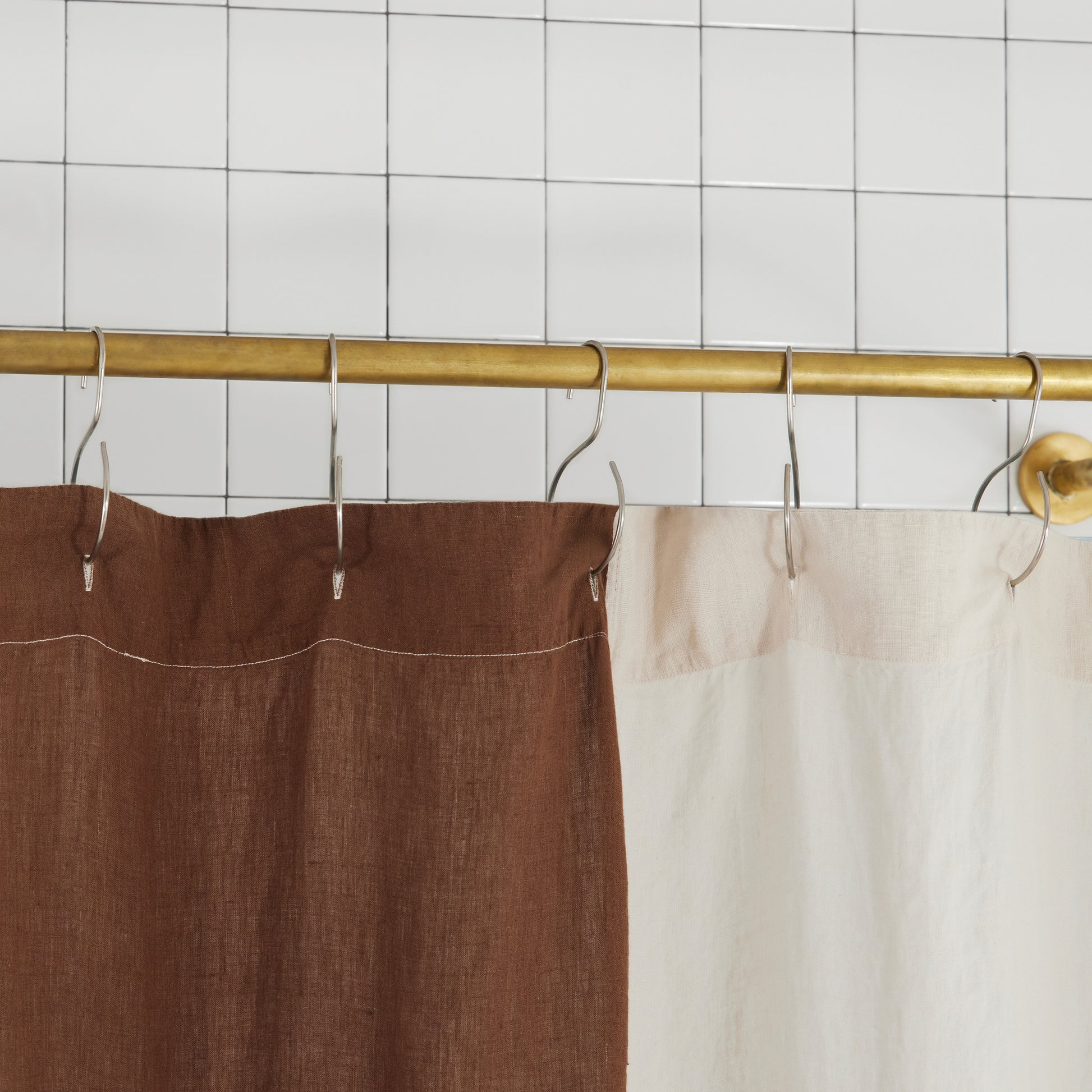 top hem of blue and brown checker linen shower curtain to show button holes for shower curtain hooks to hang from.