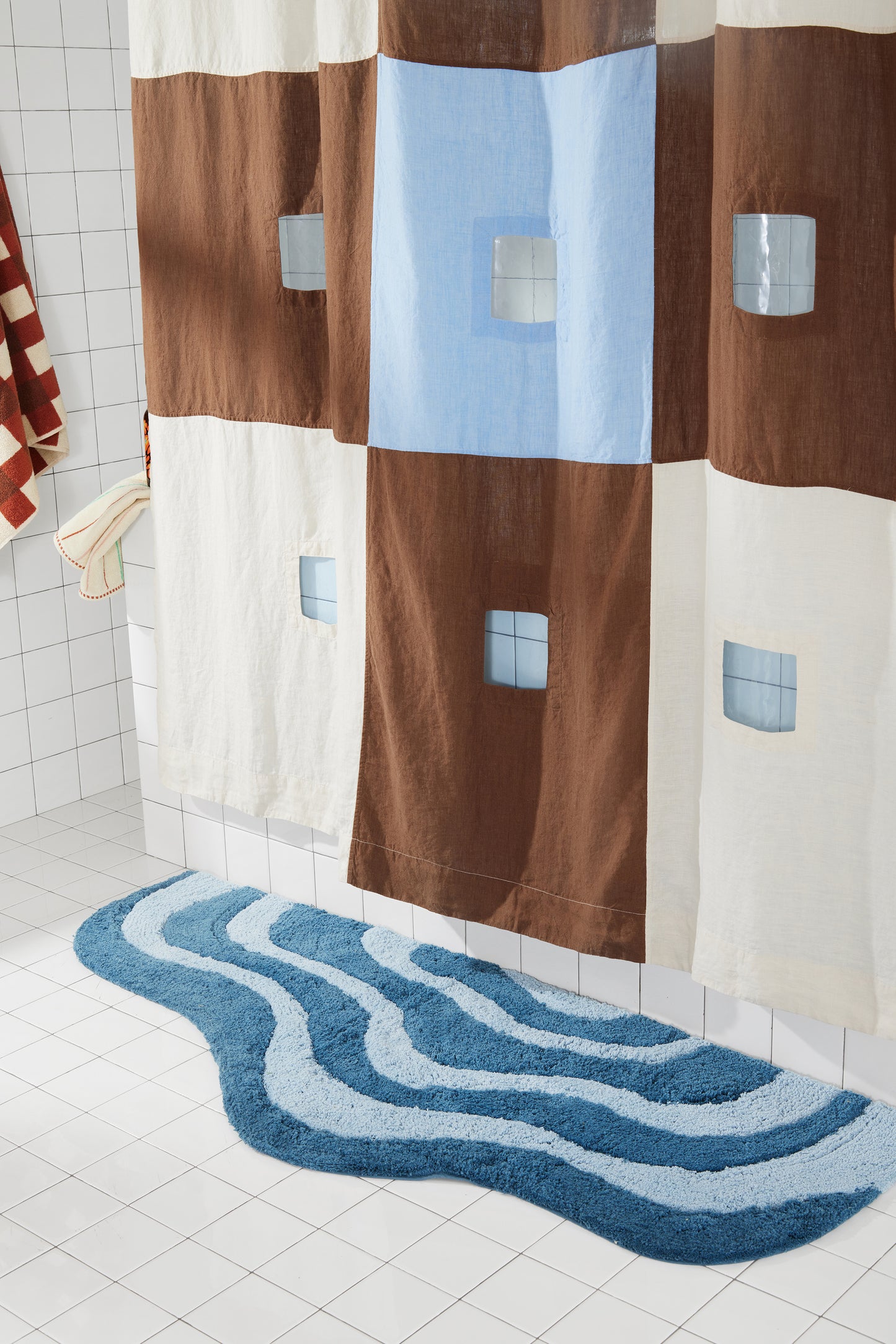 Blue and Brown checker linen shower curtain hangs in window light