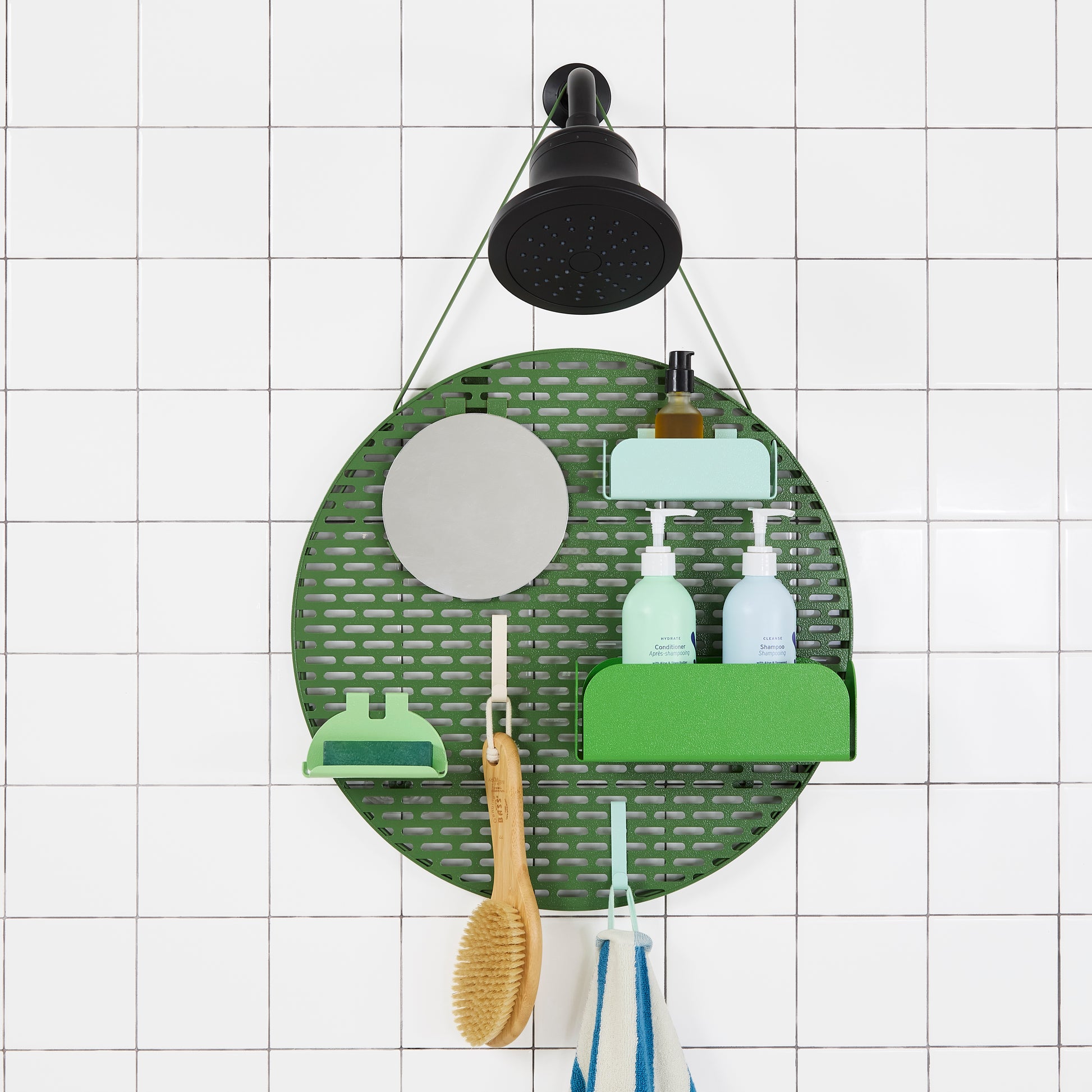 The spot modular shower organizer with shelving pieces arranged and holding products, hanging in a white tiled shower.