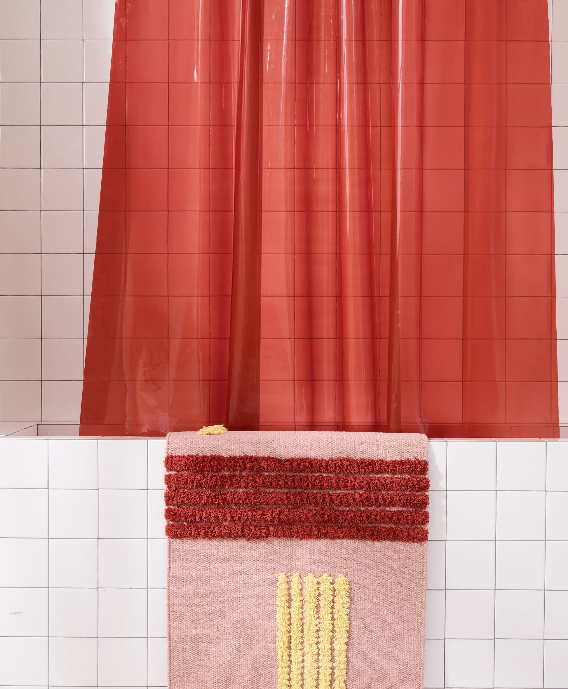 Detail view of Sun Shower Brick hanging in white tiled bathtub styled with rose reyes rug.