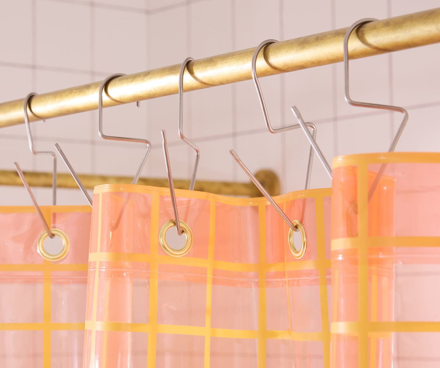 Top seam of sun shower curtain hanging on brass bar with silver venice hooks.