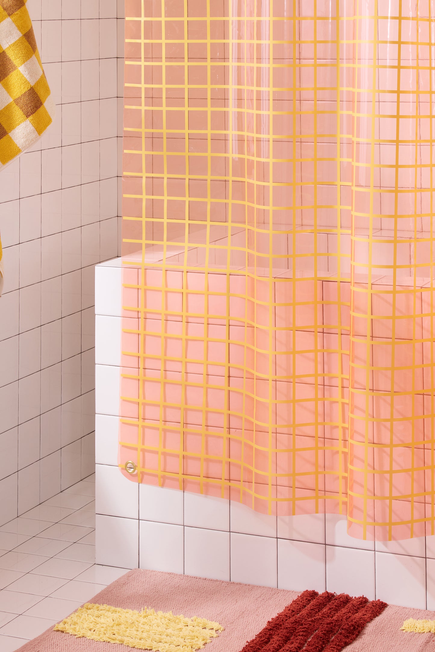 Bottom left corner of sun shower curtain in peony styled with checked and striped bathroom accessories.