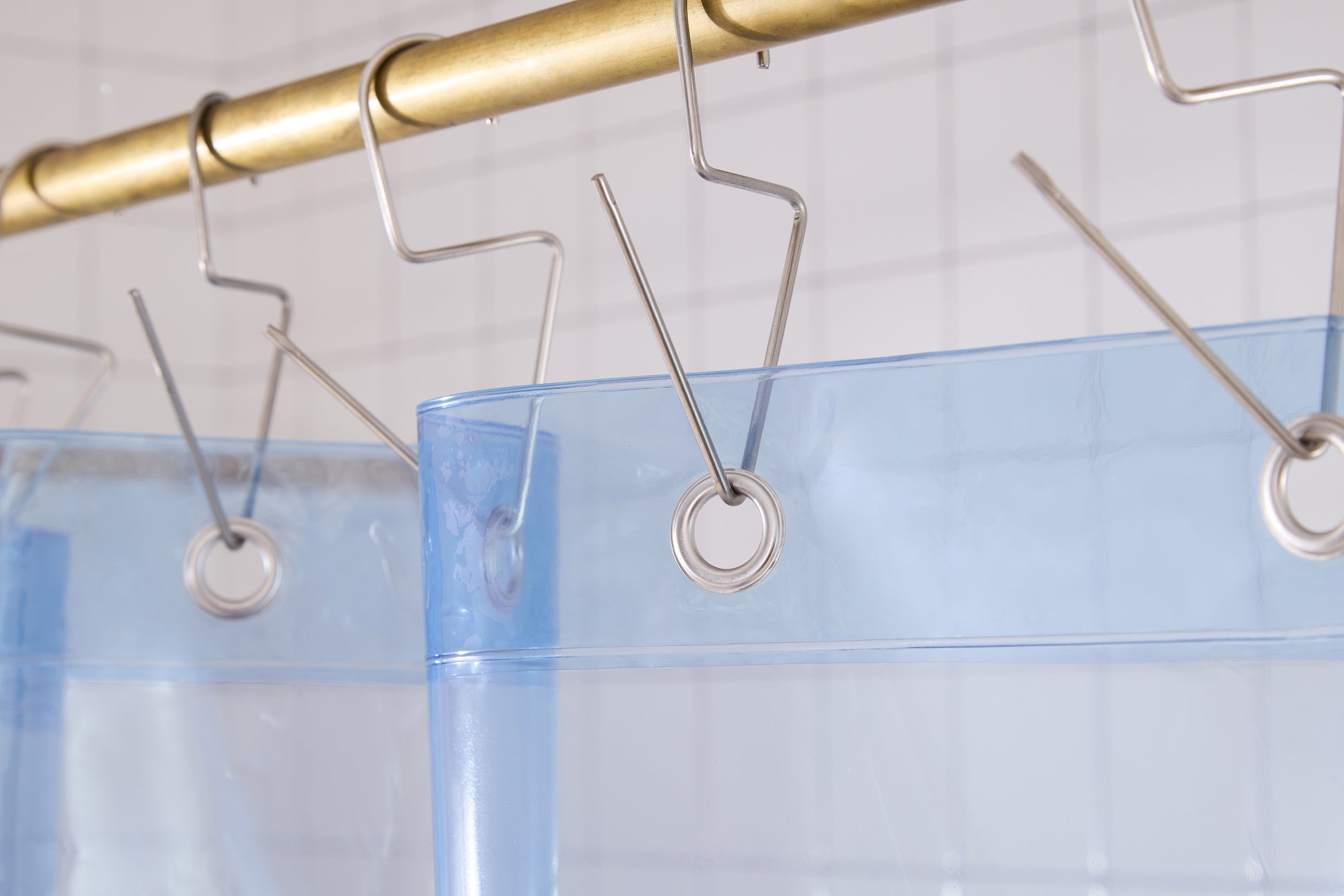 Orient Sun Shower deep sea detail view of silver grommets and hooks hanging from shower curtain rod.