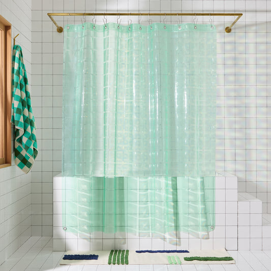 Mint colored shower curtain hangs in white tiled bathroom.