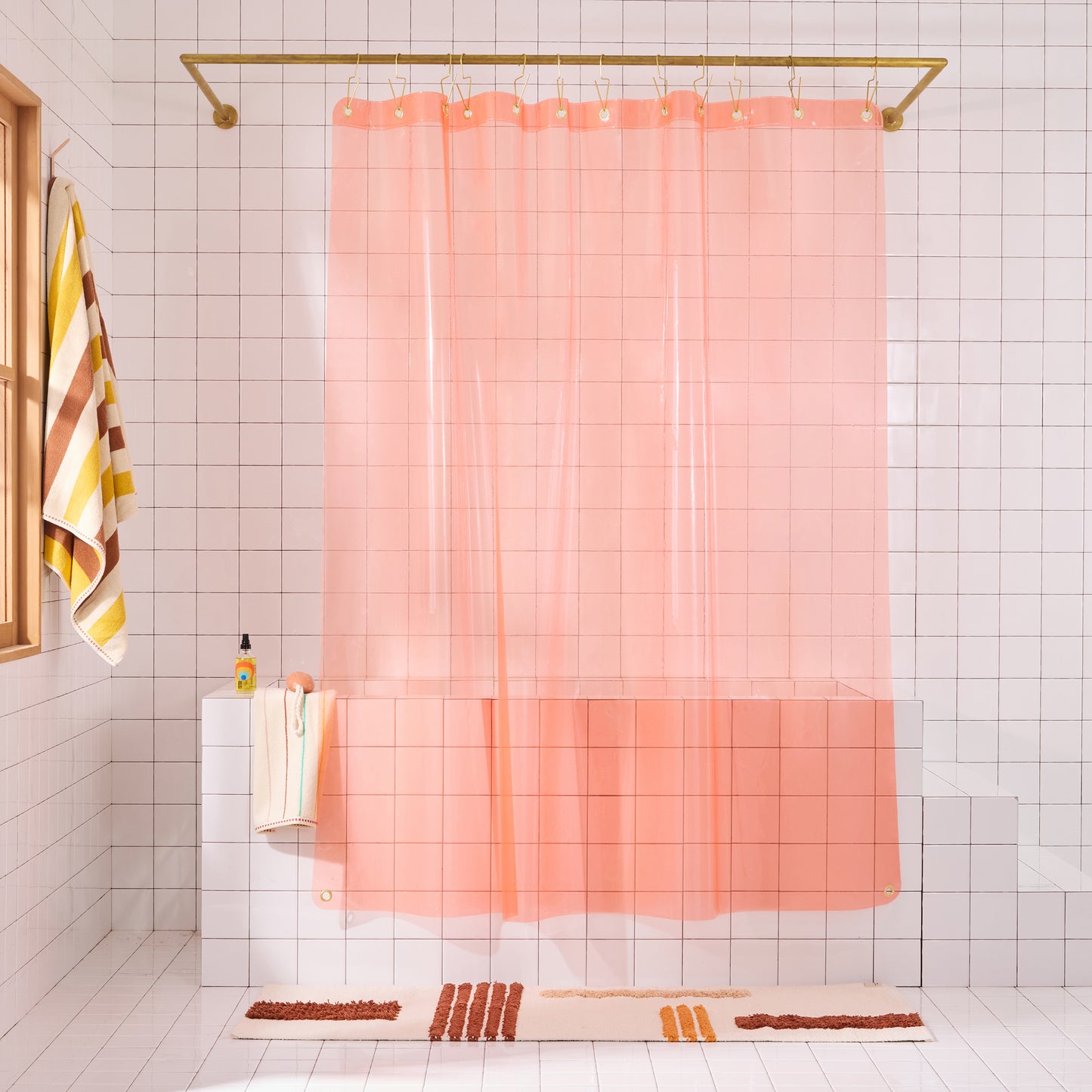 Sun shower curtain in peony hanging over bathtub styled in a white tiled bathroom with rose reyes rug and catalina bath sheet in canyon.