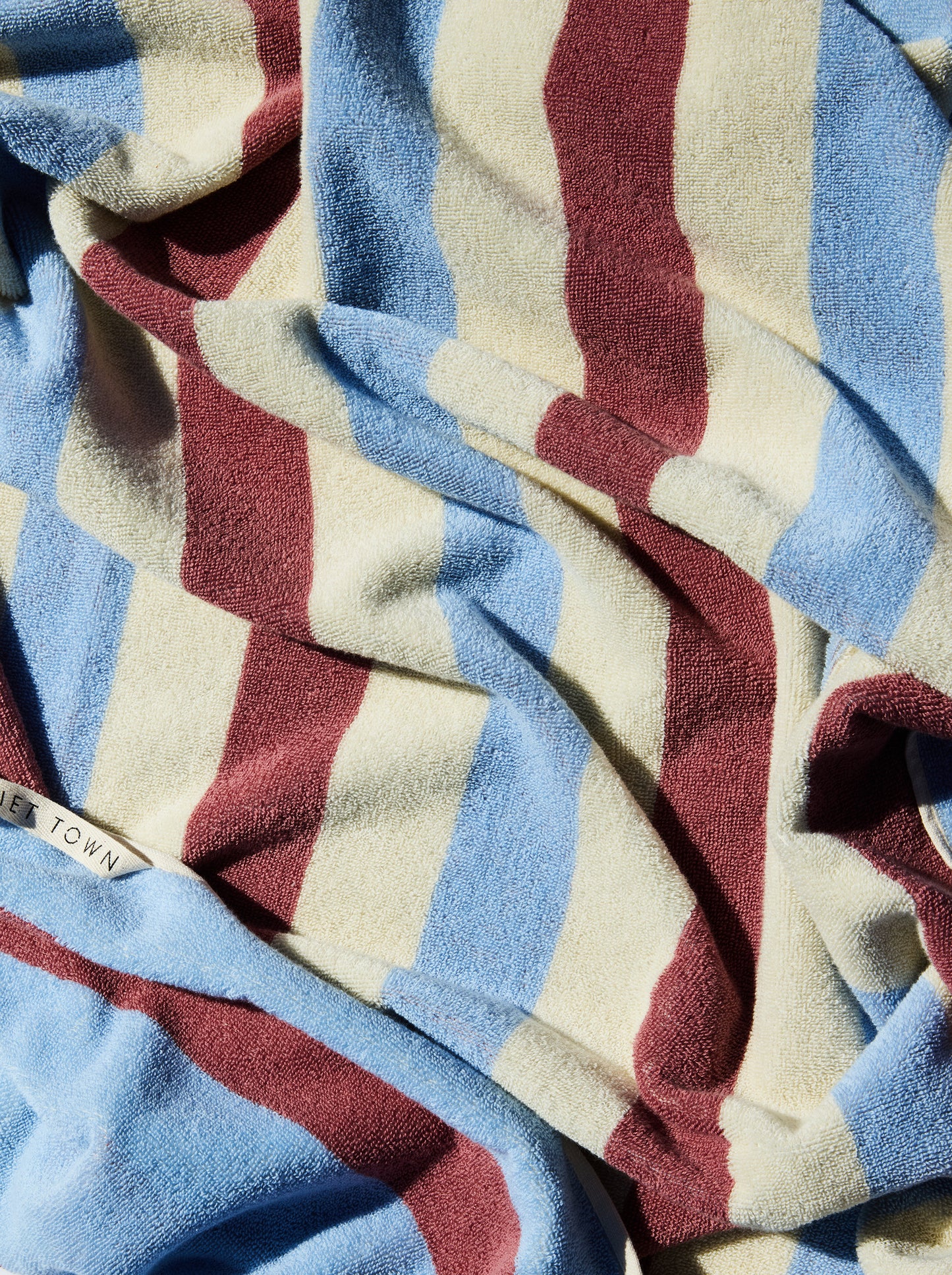 Close-up of striped blue, rose, and cream colored reversible towel.