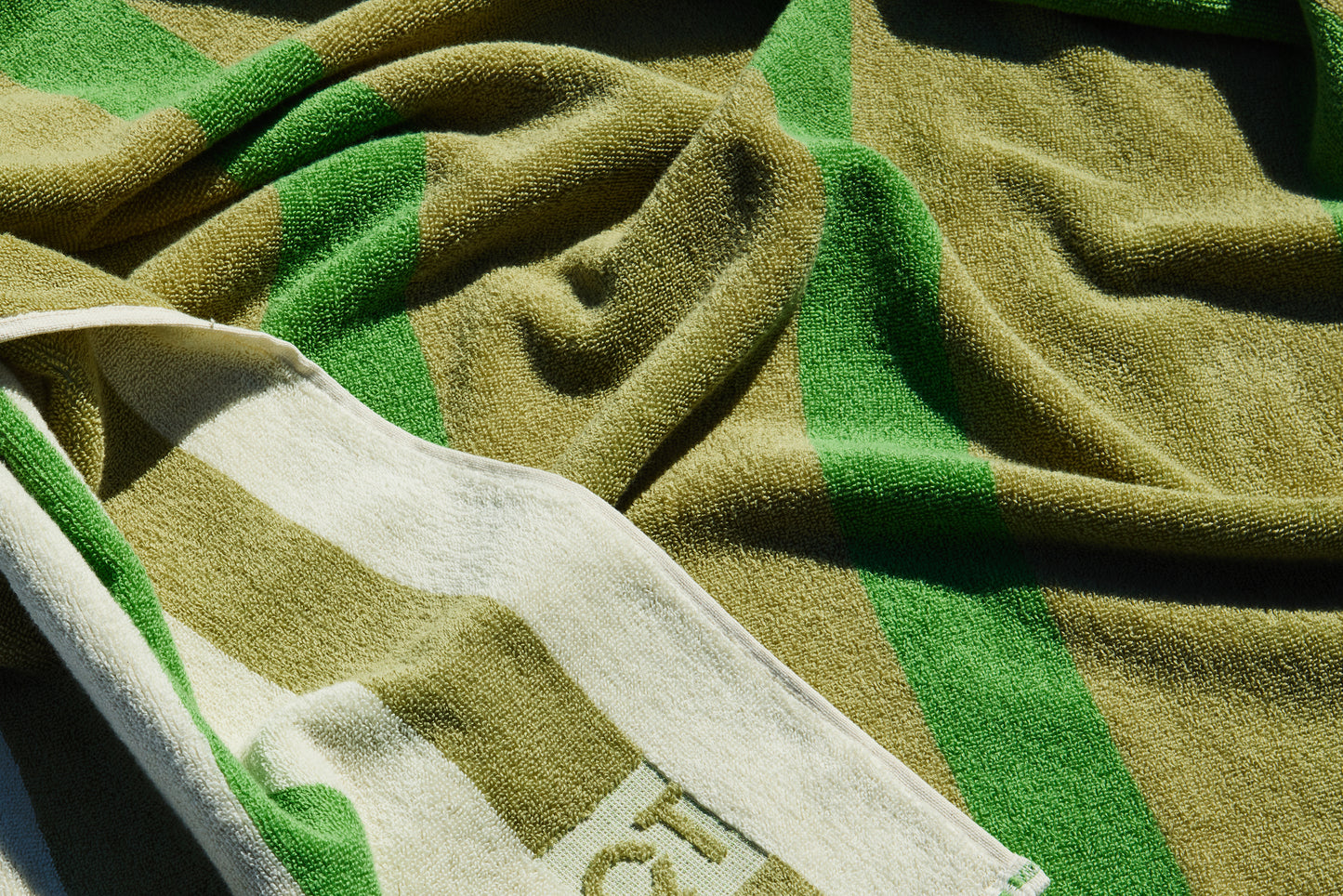 Green and cream striped, reversible towel draped on floor.