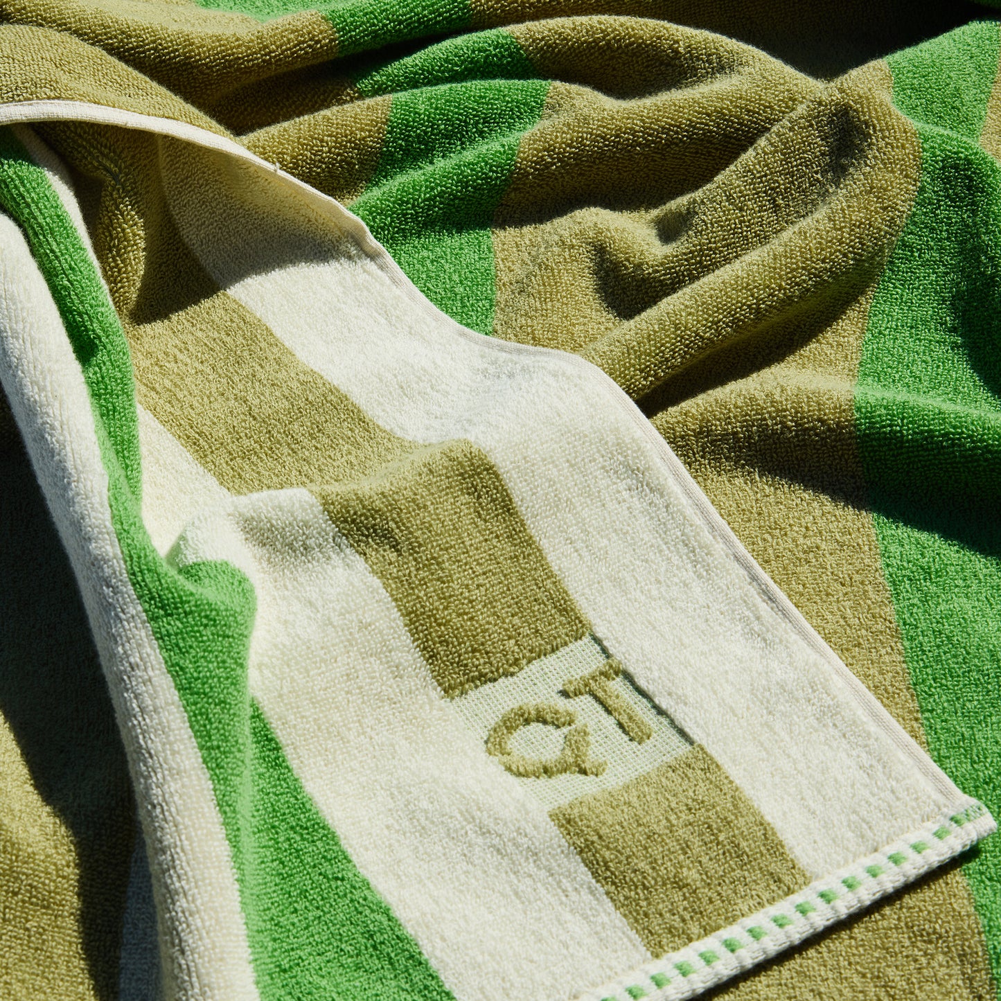 Green and beige towel with 'QT' branding