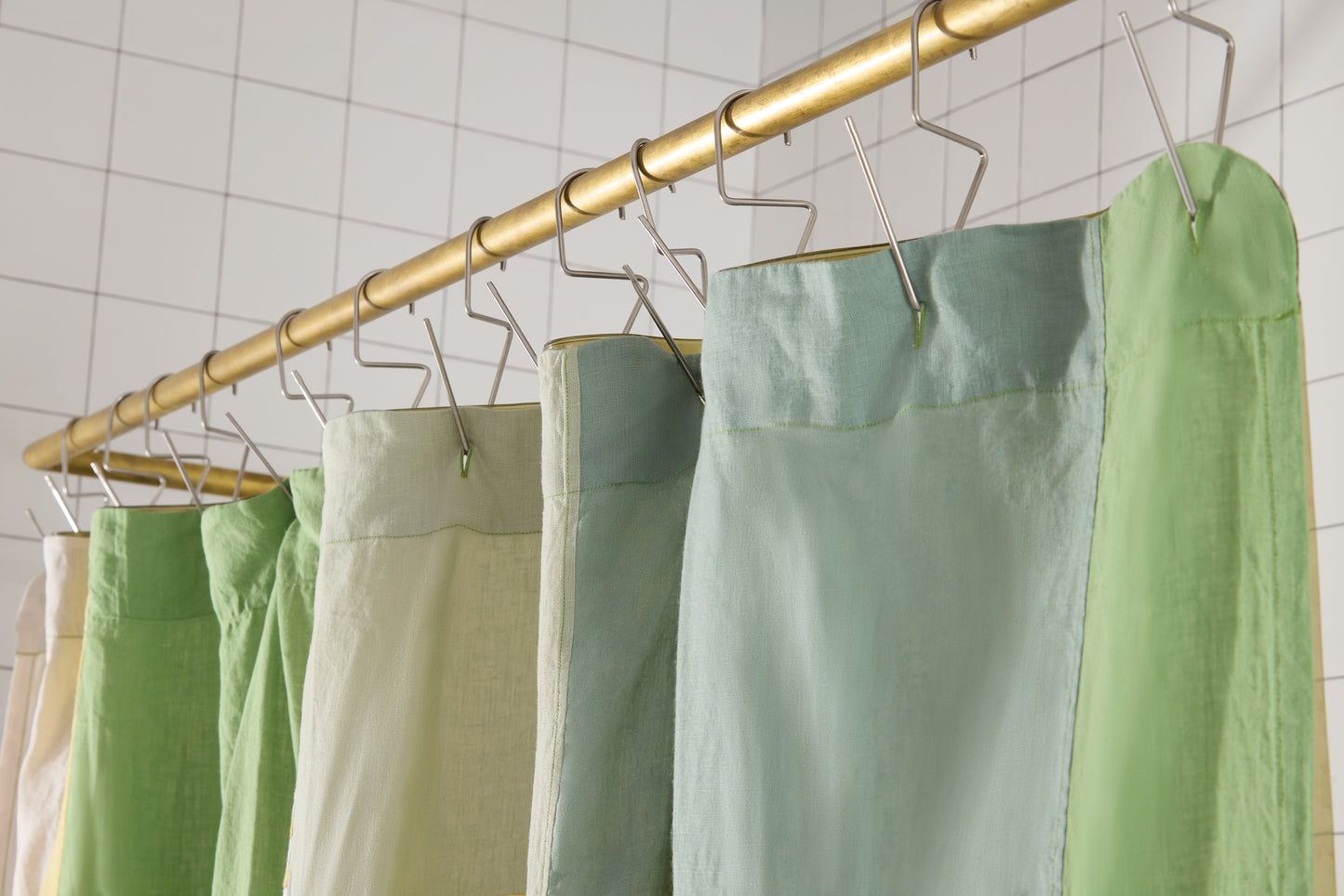 Green shower curtain hanging on shoer rod off hooks