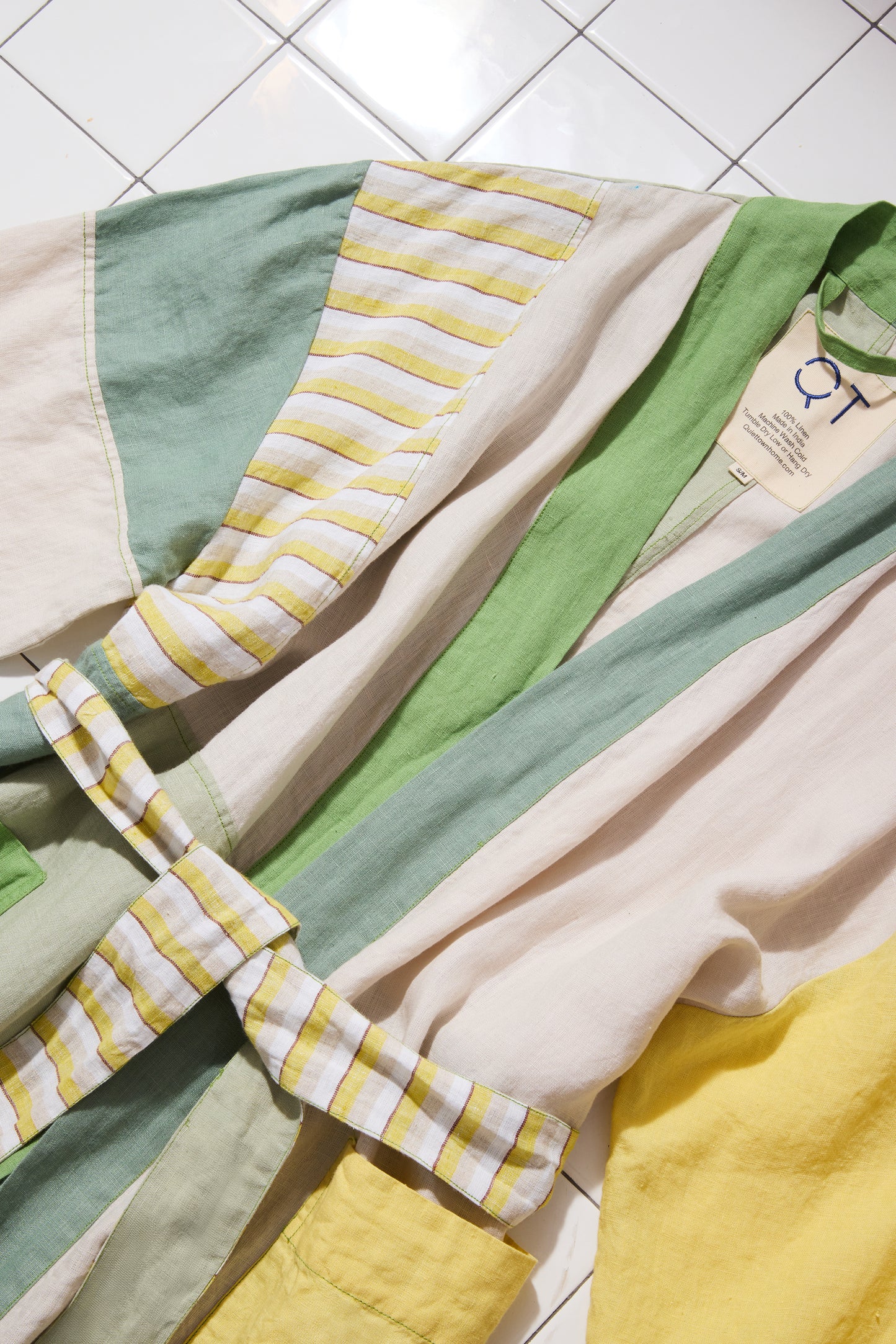 Cropped in photo of green and yellow bathrobe on a tiled floor.