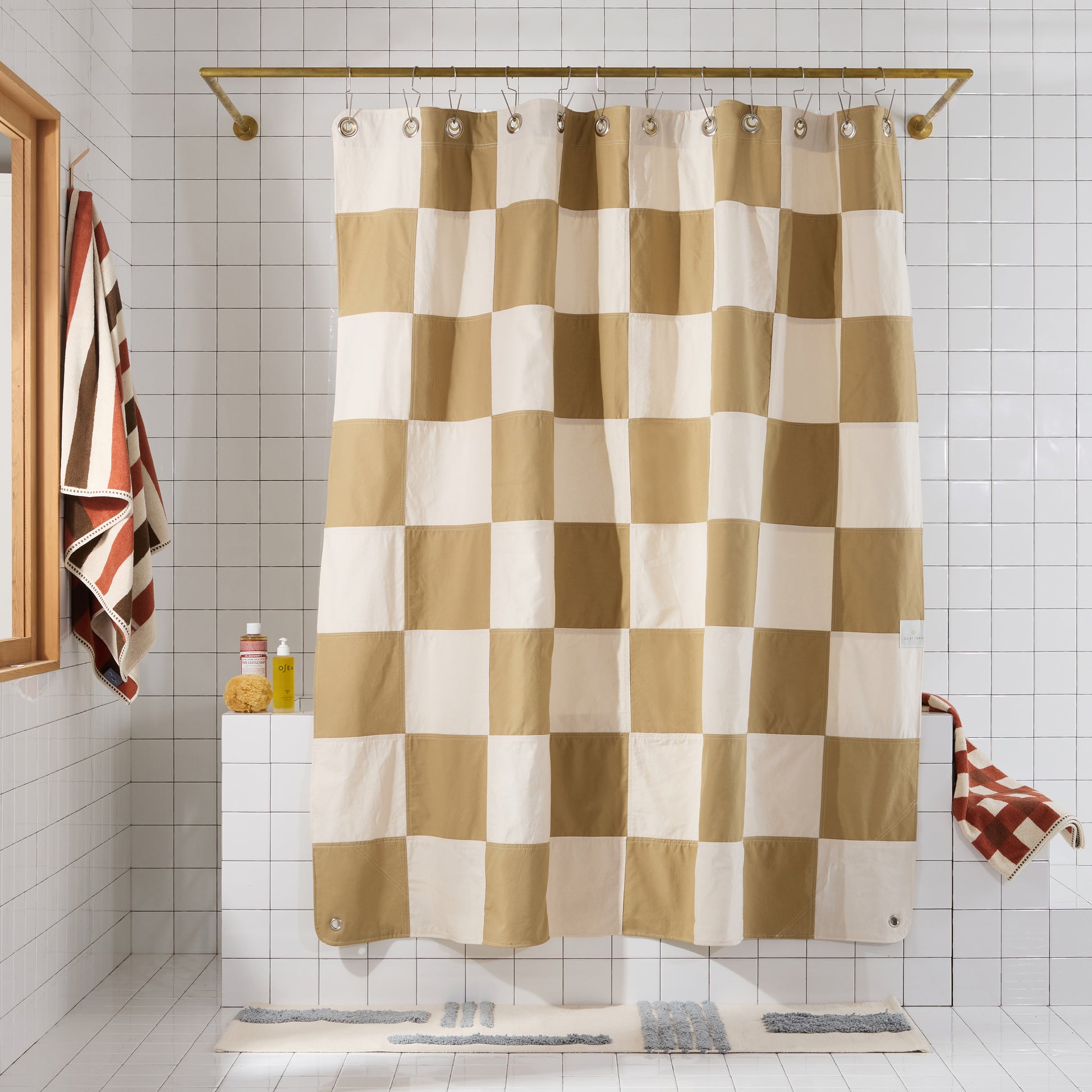 Checkered shower curtain in a bathroom with tiled walls and patterned towels.