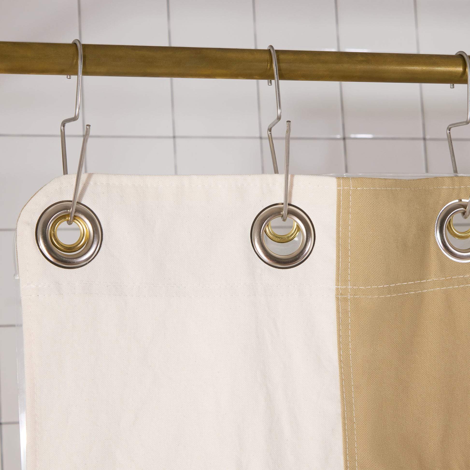 close cropped image of shower curtain hanging off of silver grommets and silver hooks.