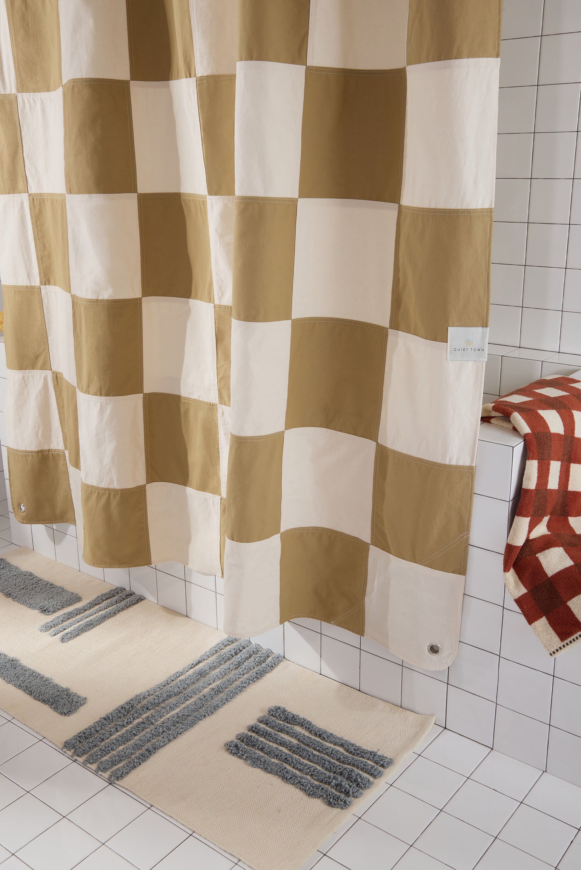 Checkered shower curtain in a bathroom with tiled walls and floor.