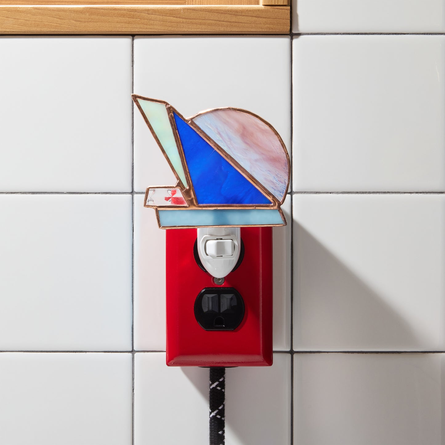 Decorative night light with stained glass design on a tiled wall