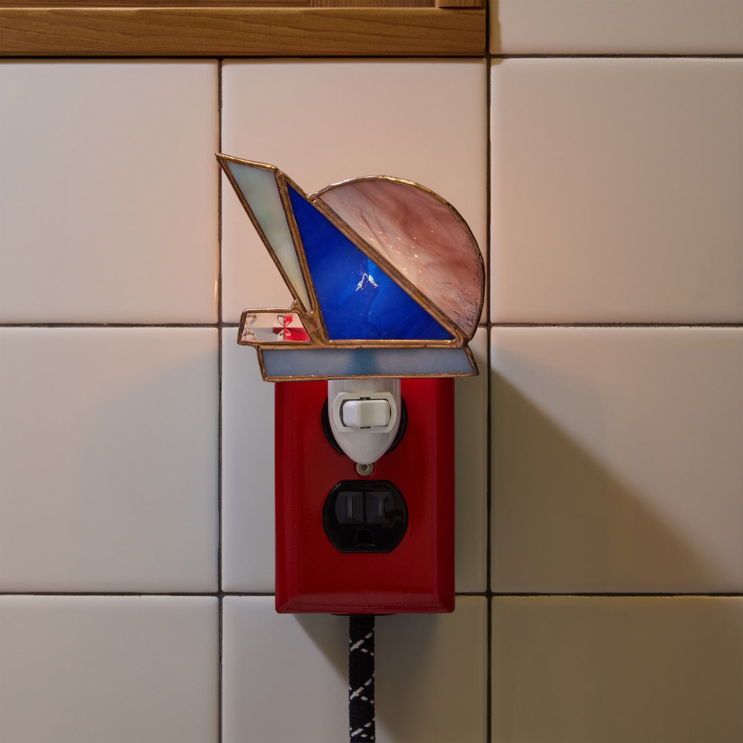 Decorative night light with stained glass design on a tiled wall.