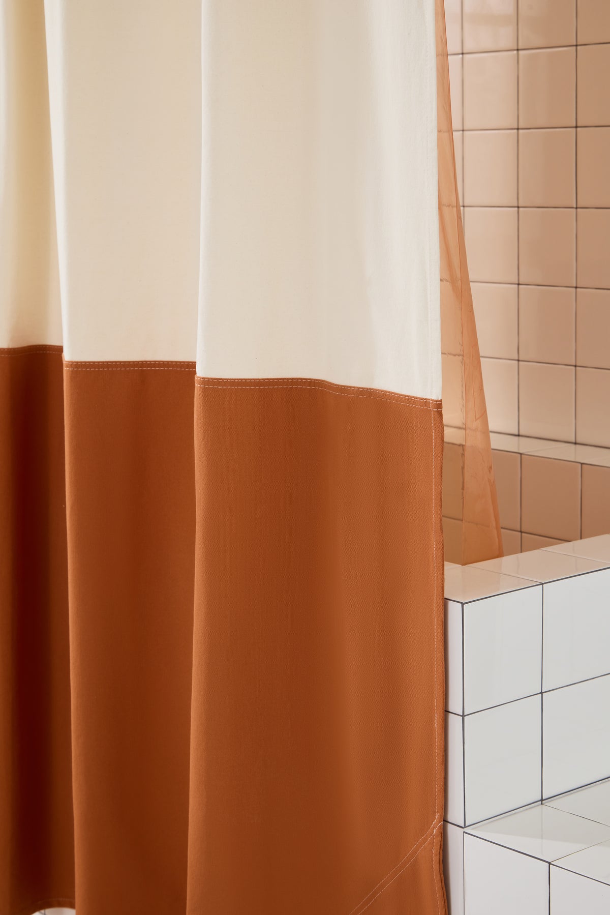 Close-up view of Orient Clay colorblock curtain hanging next to tiled walls