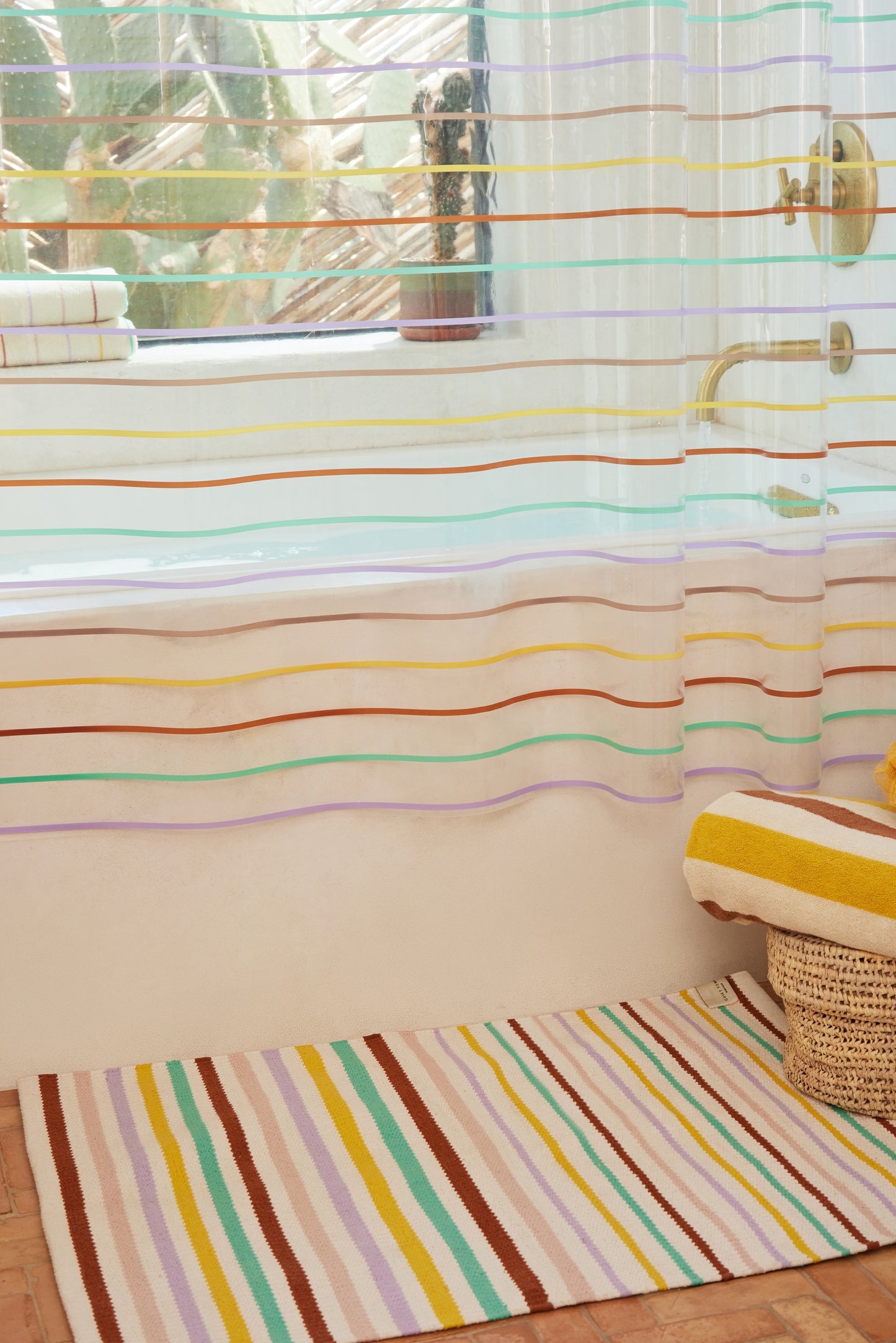multi color striped rug styled on the floor of a bathroom with the prism sun shower curtain and catalina canyon bath sheet