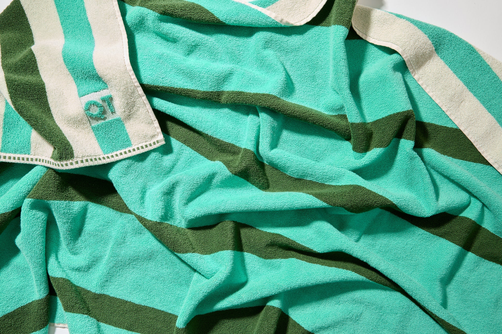 Close up of catalina bath sheet in pine with color to color stripes in jade and pine.