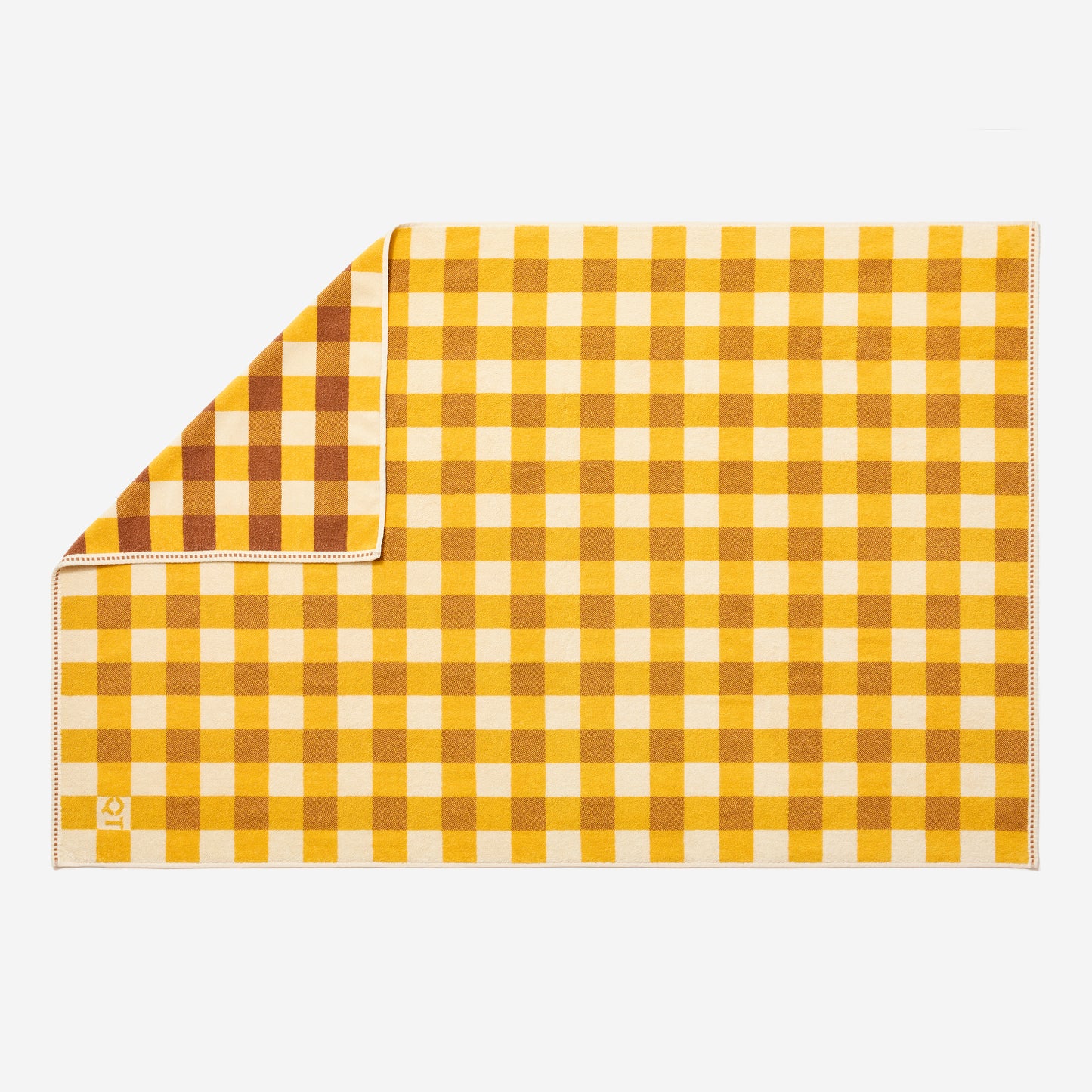 Tam bath sheet in canyon laid flat with one corner flipped up showing more saturated side of checks.