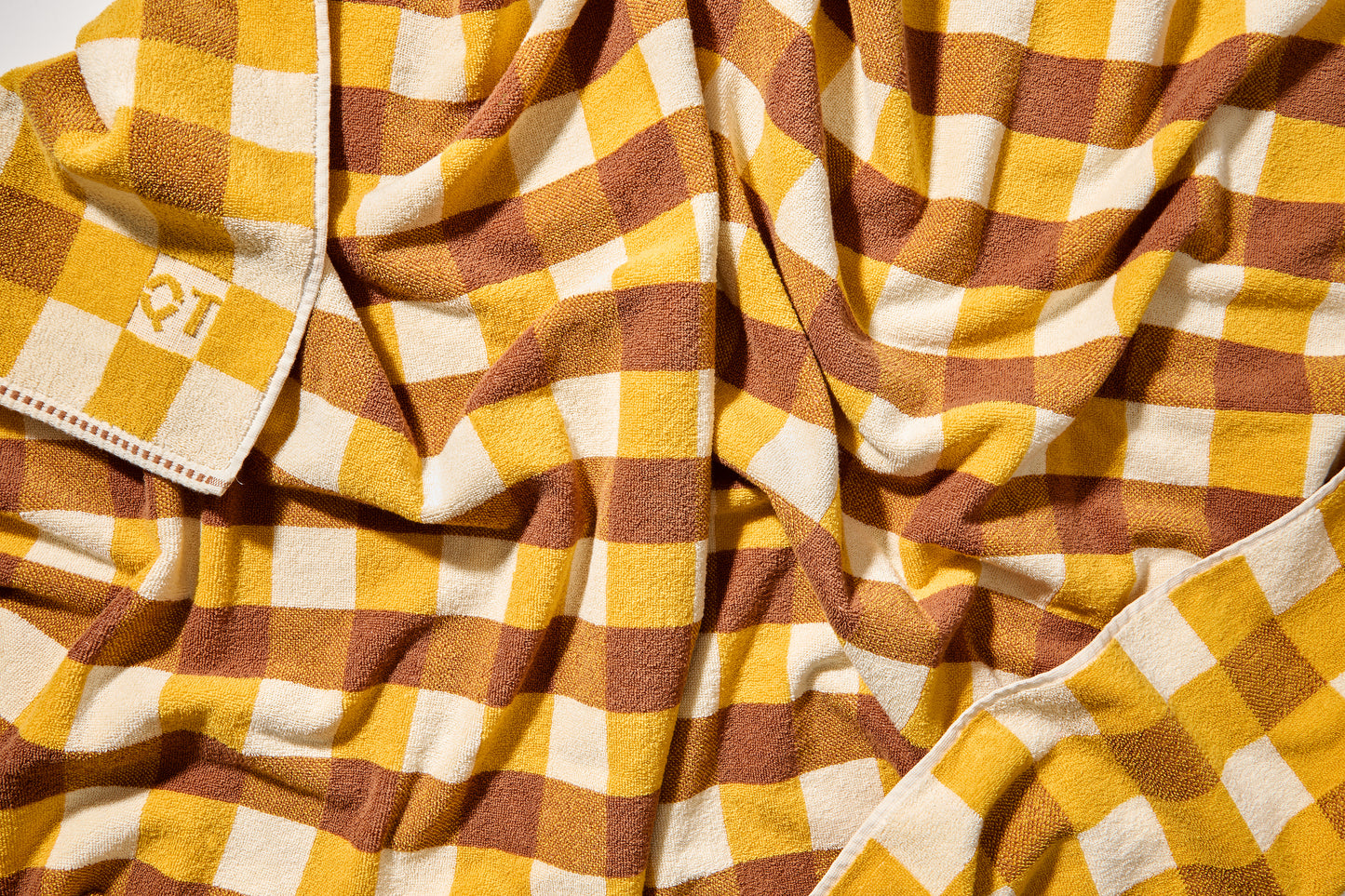Scrunched up shot of tam bath sheet showing checked pattern of honey, yellow, and cream.
