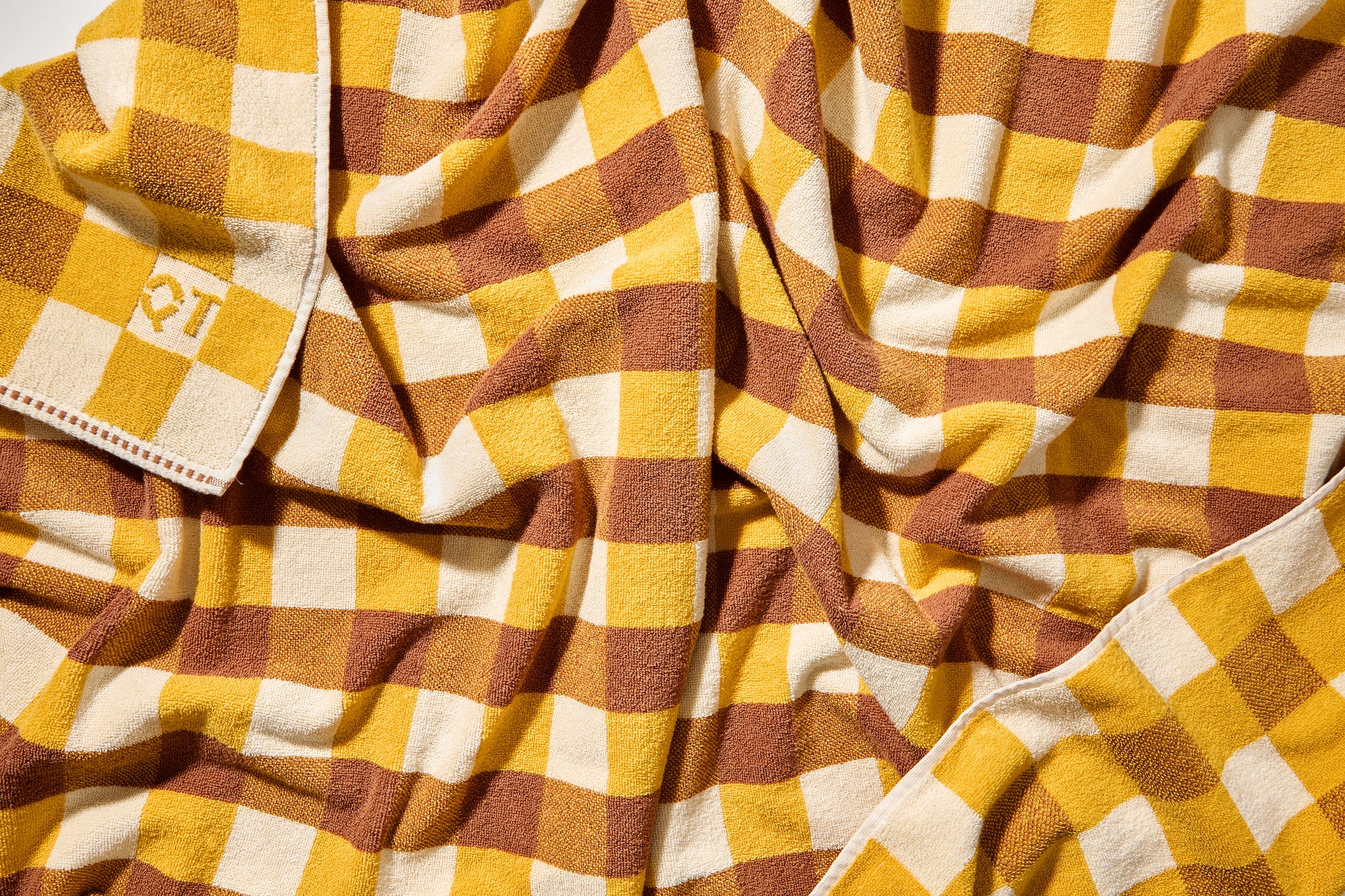 Scrunched up shot of tam bath sheet showing checked pattern of honey, yellow, and cream.