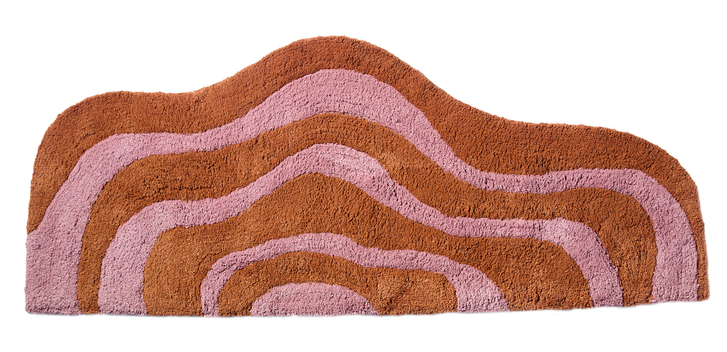 Wave shaped honey and rose striped bath mat runner in 56"x22" size with white background.