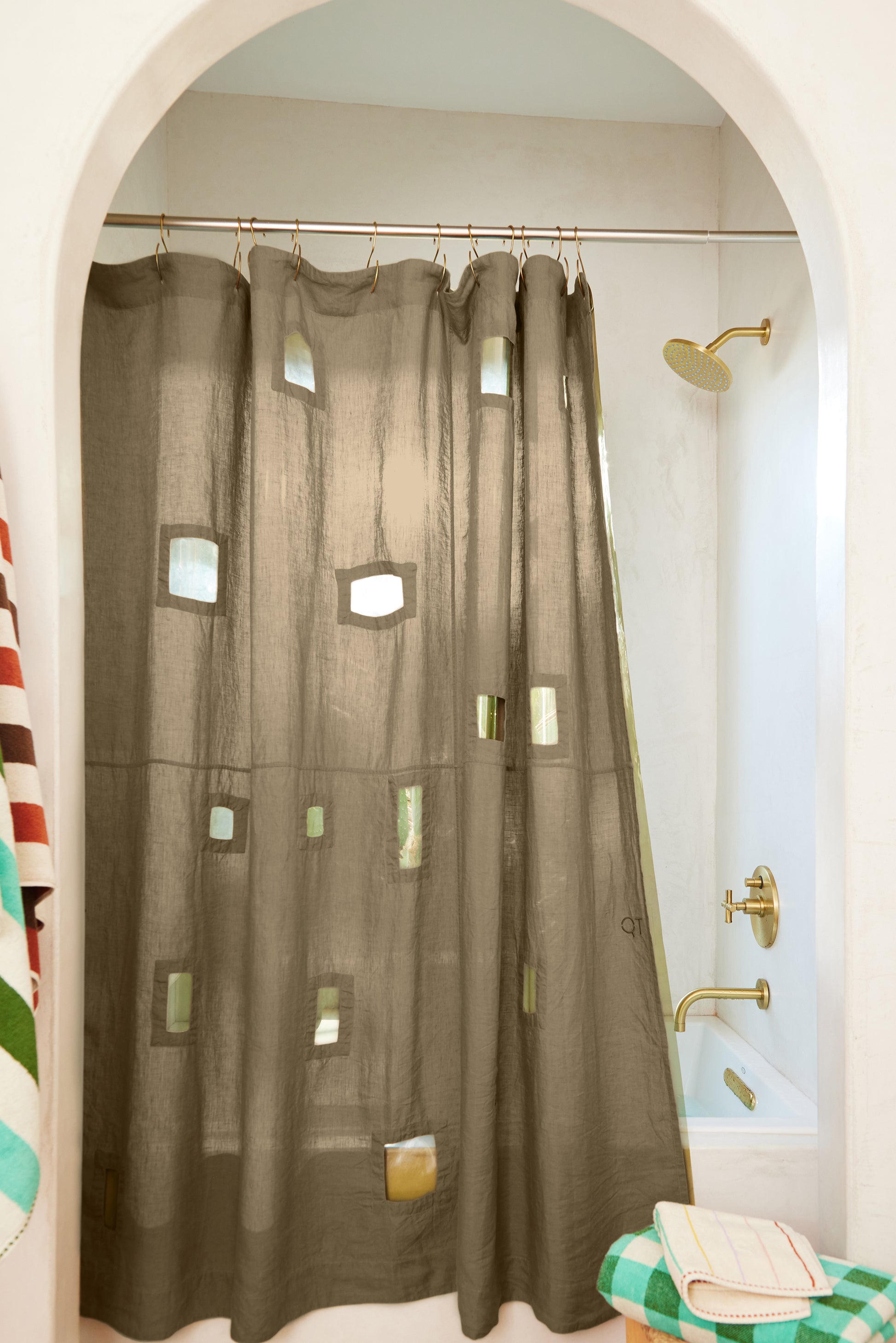Ronchamp linen curtain in olive styled in bathroom with arched doorway.