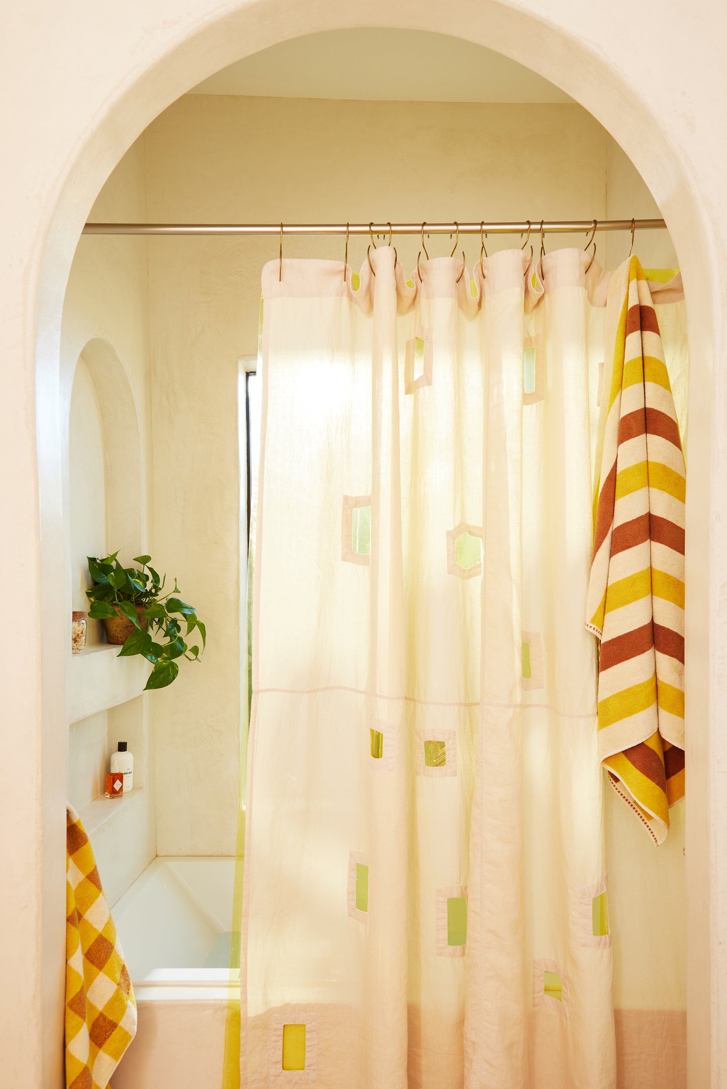 Ronchamp linen shower curtain in sand styled in a bathroom with an arched doorway.