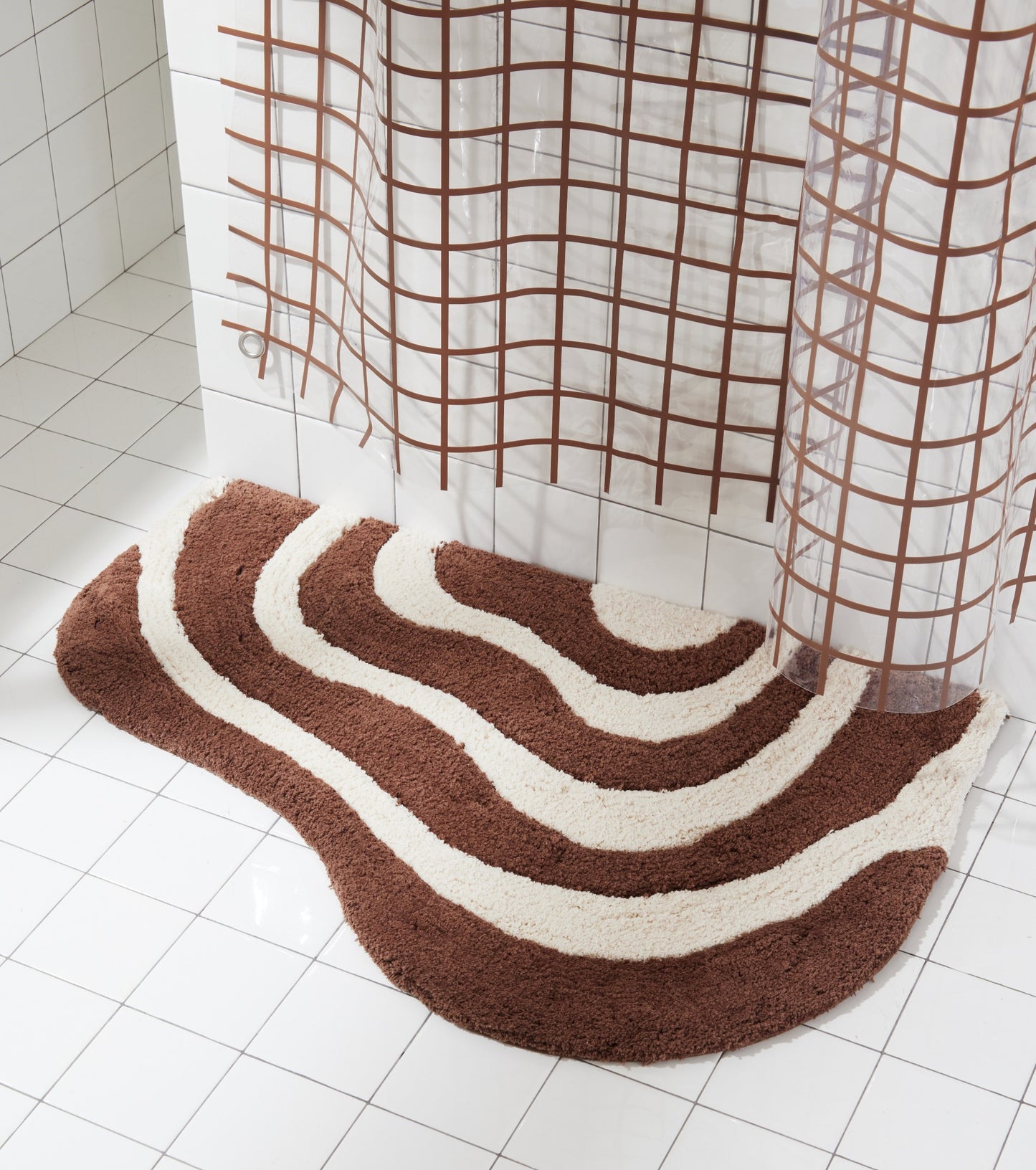 21"x31" lost coast bath mat styled beside white tiled shower and 2x2 sun shower curtain in chocolate.