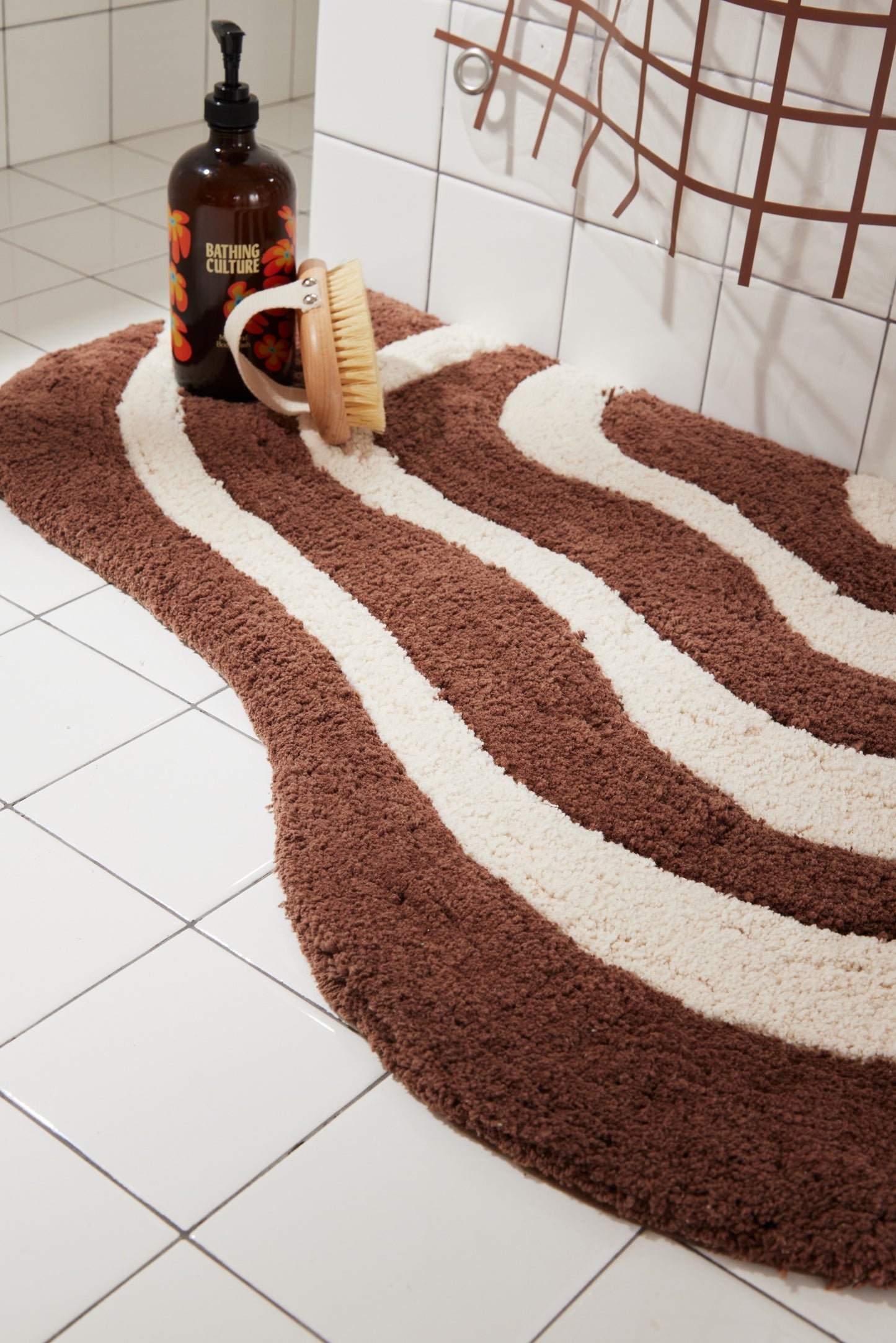 Close up of lost coast bath mat in chocolate with bathing products styled on top.