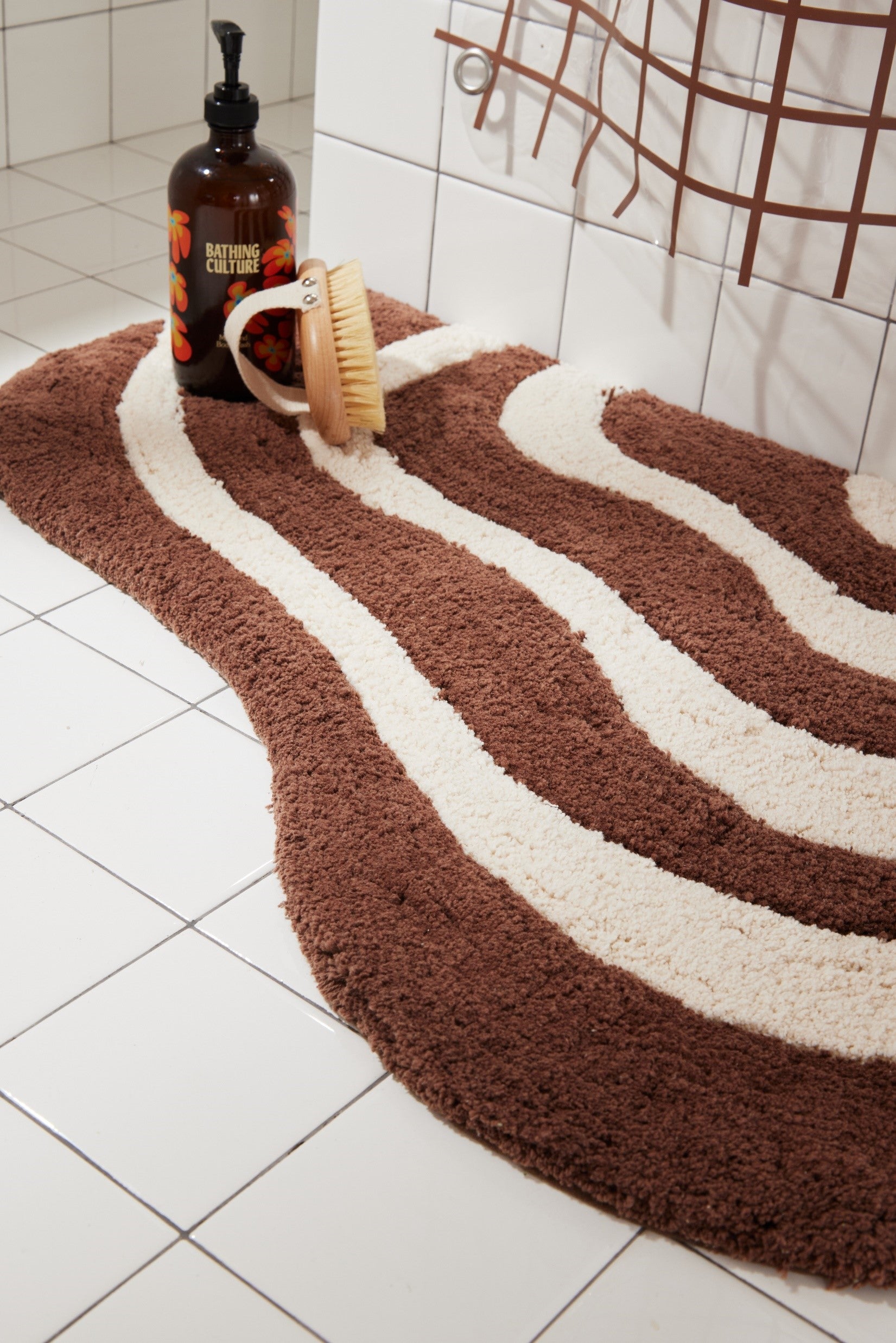 Close up of lost coast bath mat in chocolate with bathing products styled on top.